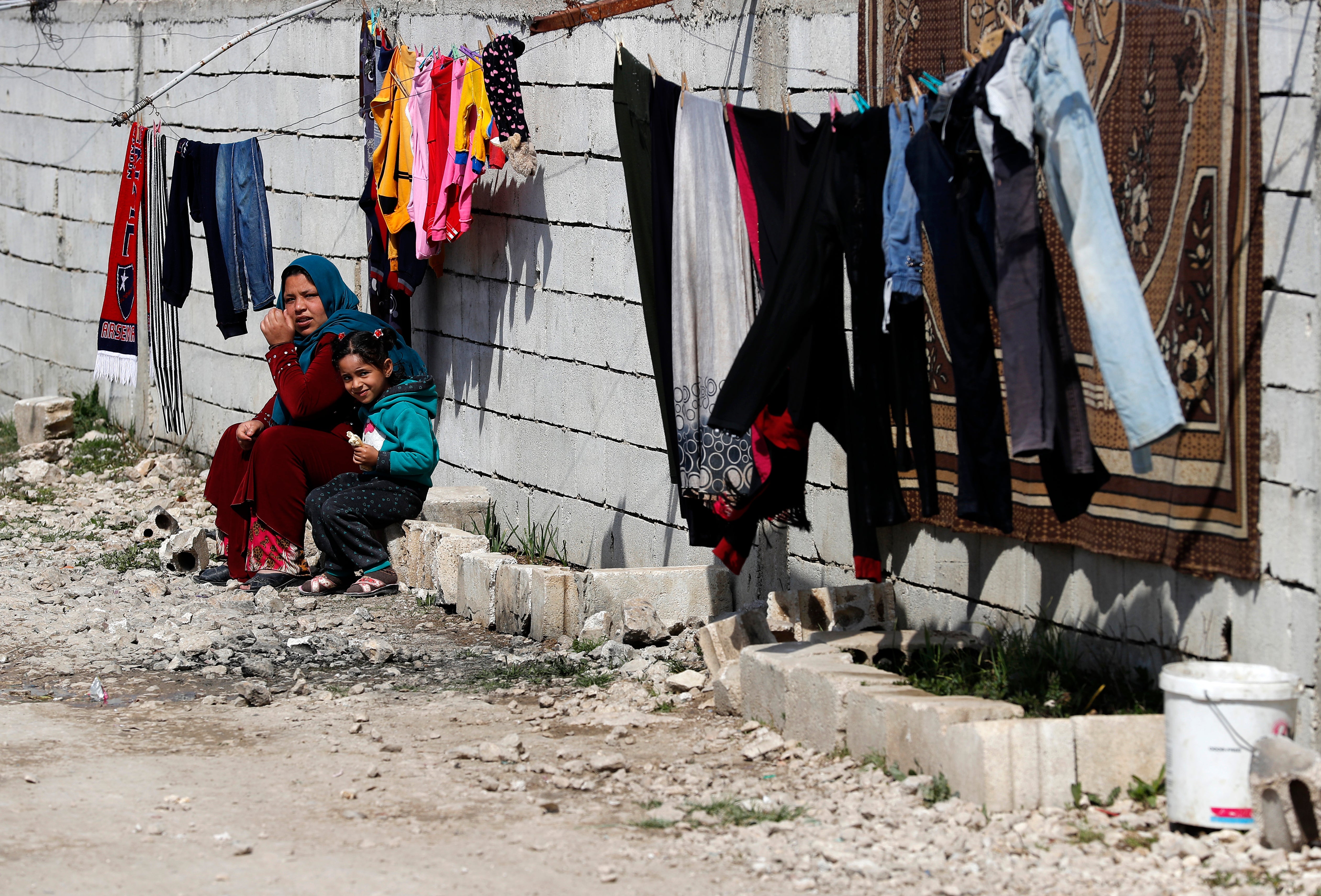 A displaced Syrian woman with her daughter sit outside their tent at a refugee camp in Bar Elias, in eastern Lebanon’s Bekaa valley, 5 March 2021