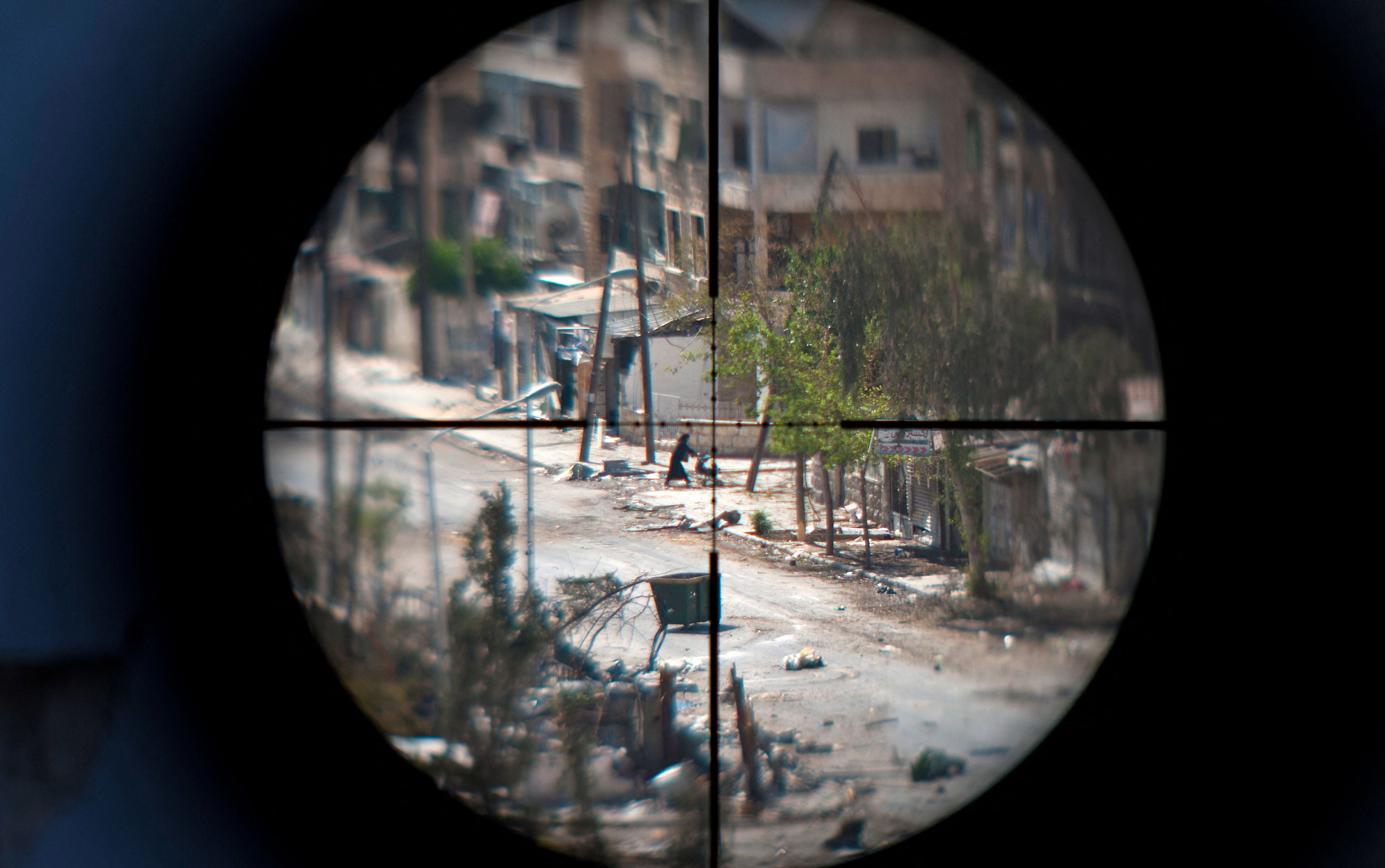 A woman and her baby are seen through the scope of an opposition fighter sniper gun, as she flees the Saif al-Dawla neighbourhood of Aleppo, in August 2012