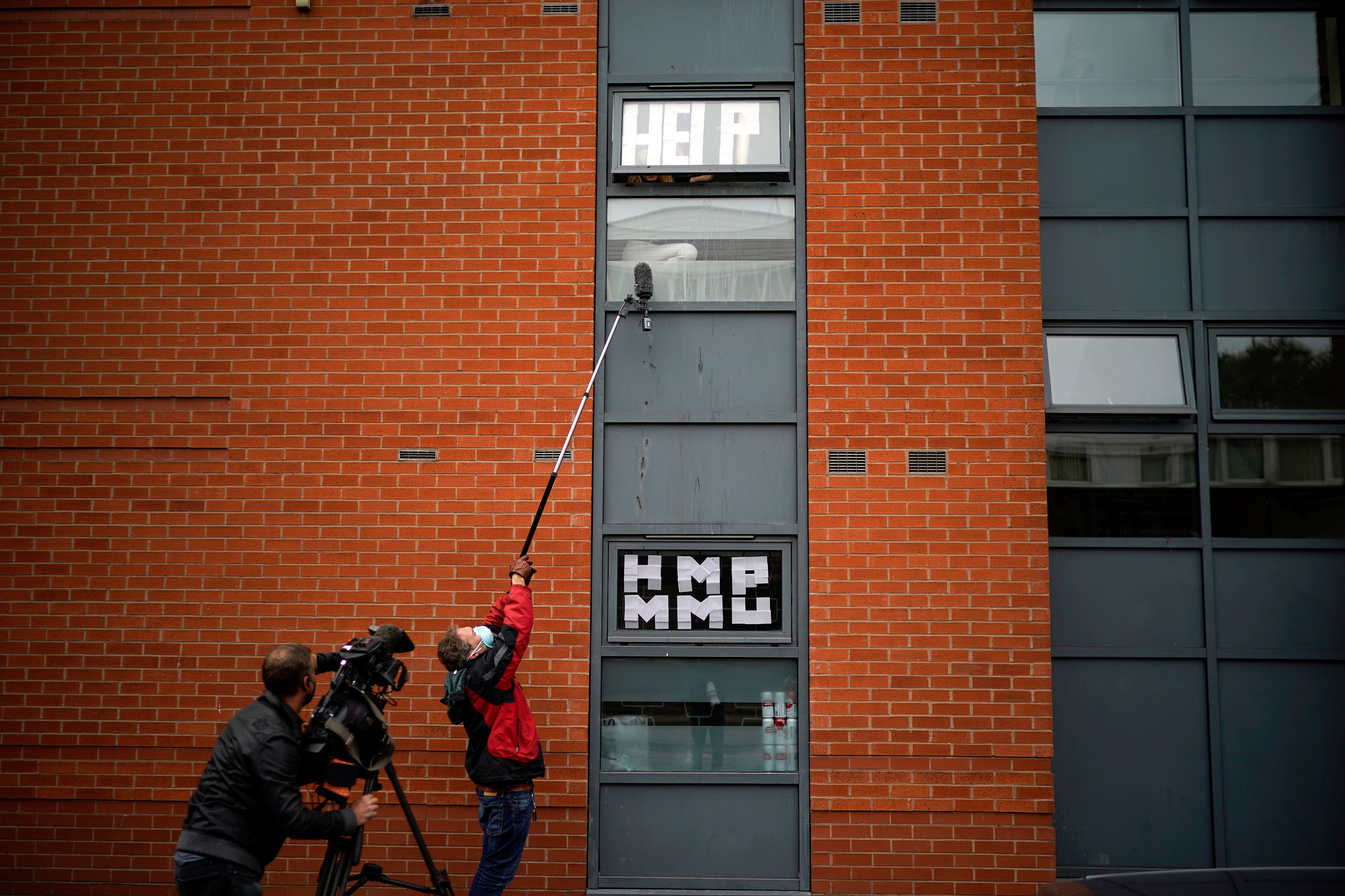 Isolating students peer out of their accommodation window as they are interviewed by a television crew on 28 September, 2020 in Manchester, England.