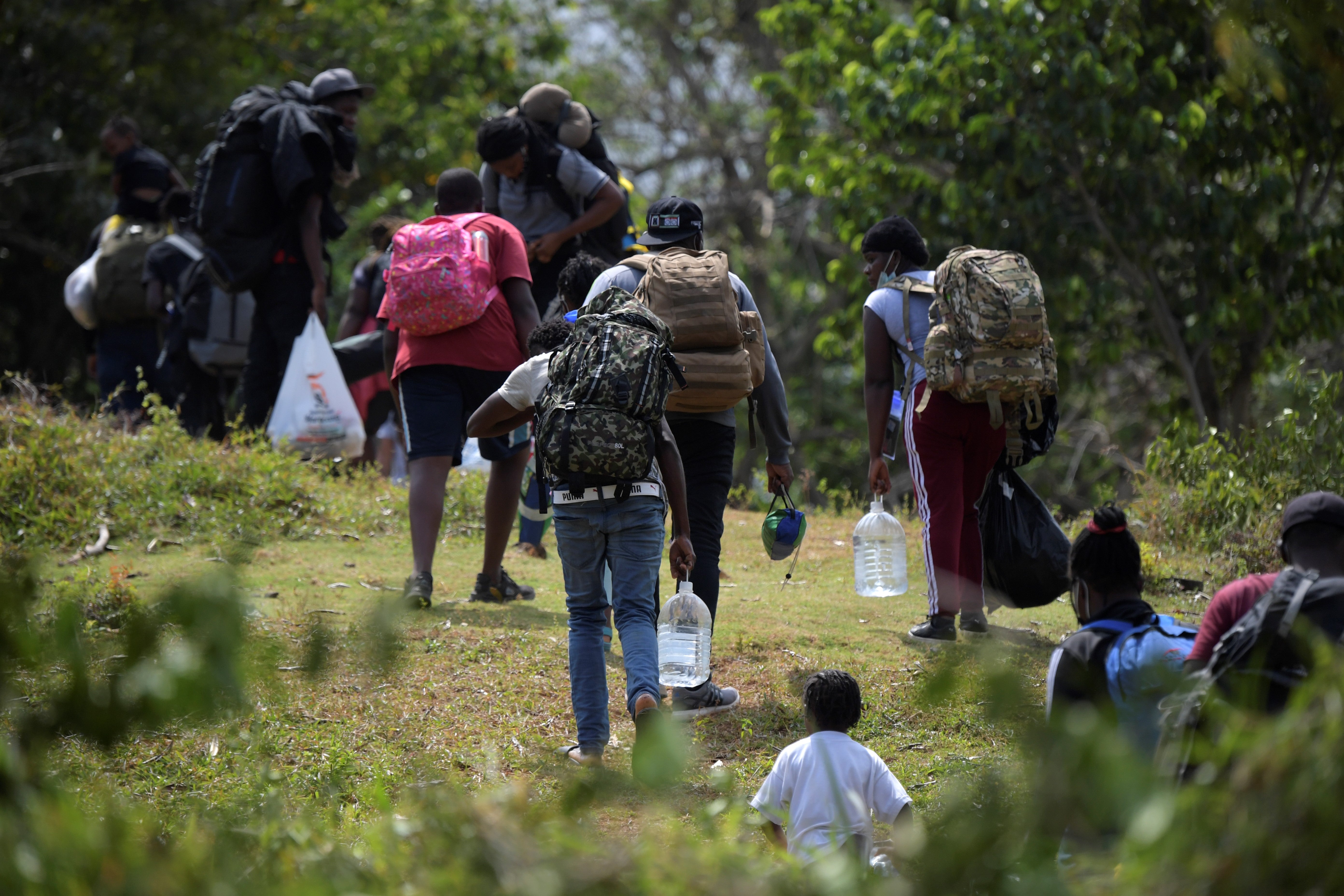 Migrants from Haiti, Cuba and several African nations who arrived to Capurgana from Necocli, both at the Caribbean Gulf of Uraba, northwestern Colombia, walk to try to cross illegally to Panama through the jungle, in Colombia, on 4 February, 2021.