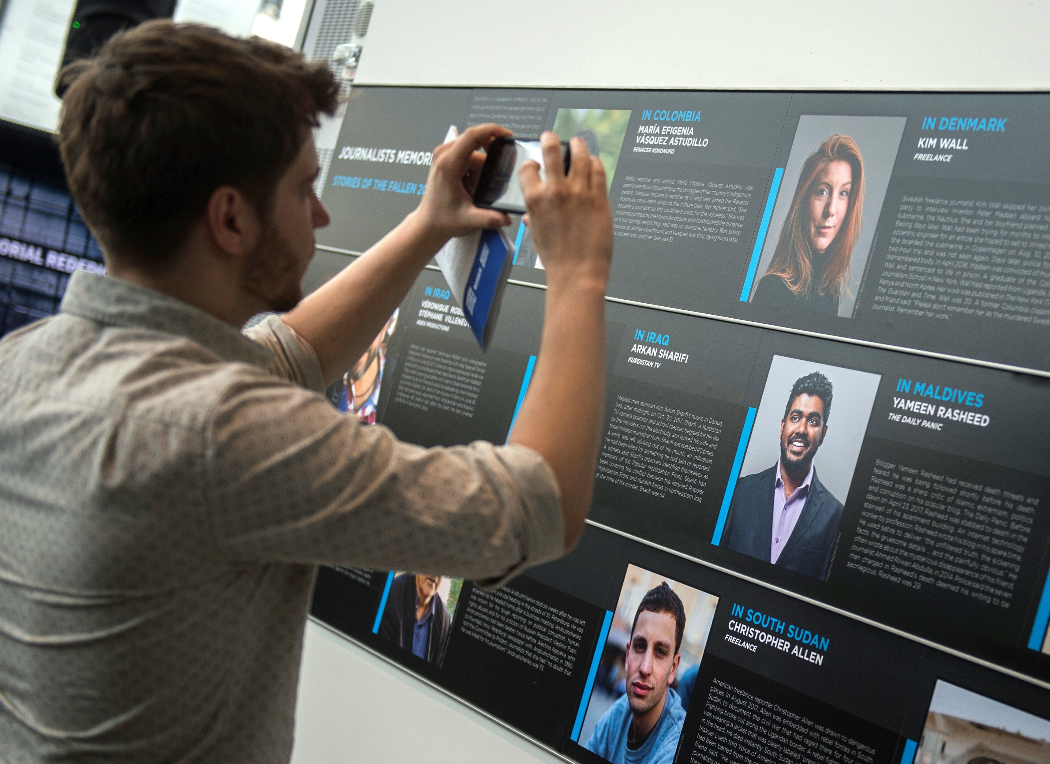 Hendrik Hinzel, a friend of Kim, takes a photo of her on a wall showing journalists killed in 2017 during a memorial event at the Newseum in Washington