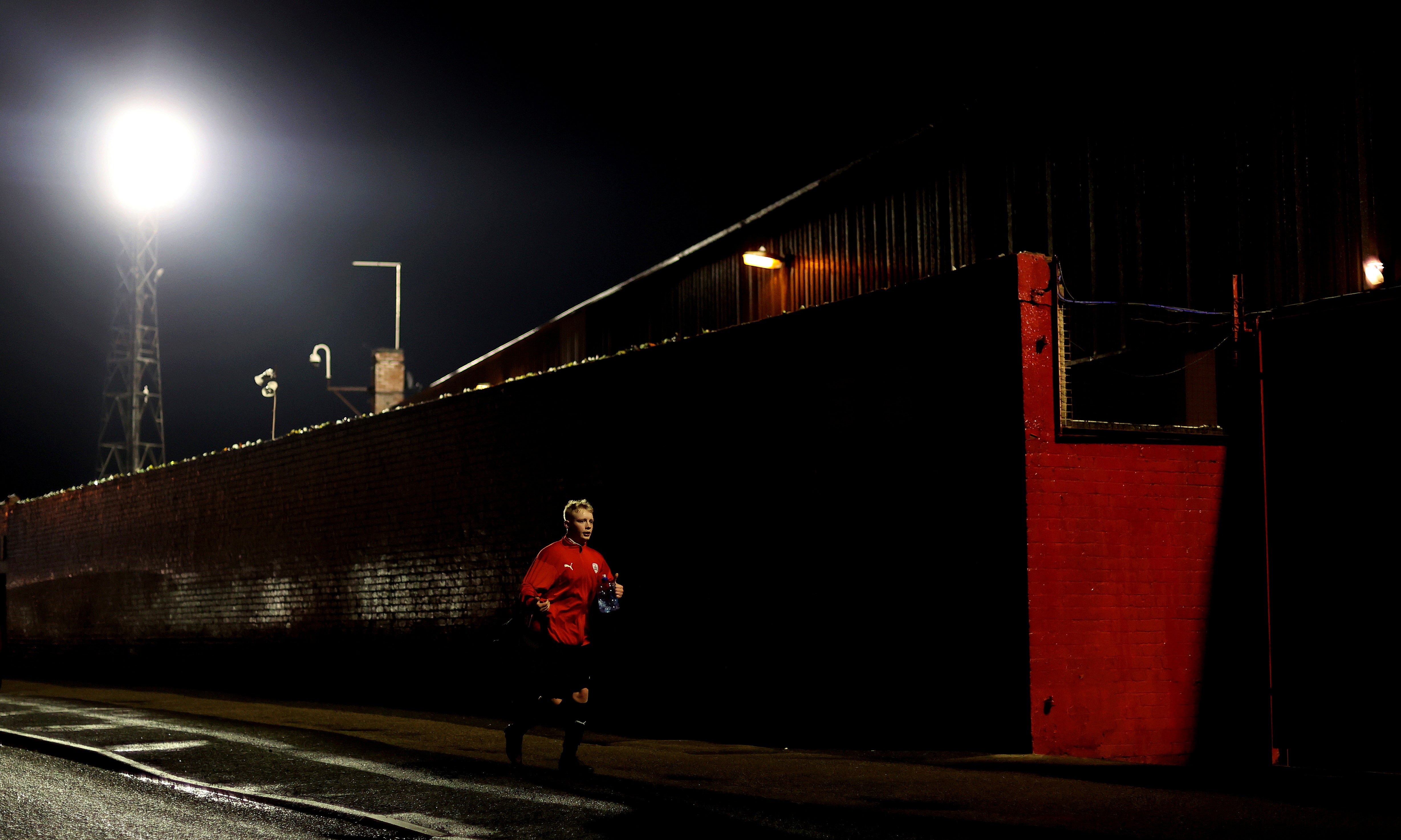 An academy player runs past Oakwell Stadium while the Barnsley and Bournemouth teams warm up inside before their Championship match in December. Normally, at this point, there would be thousands of people milling about but during lockdown the streets around stadiums are deserted