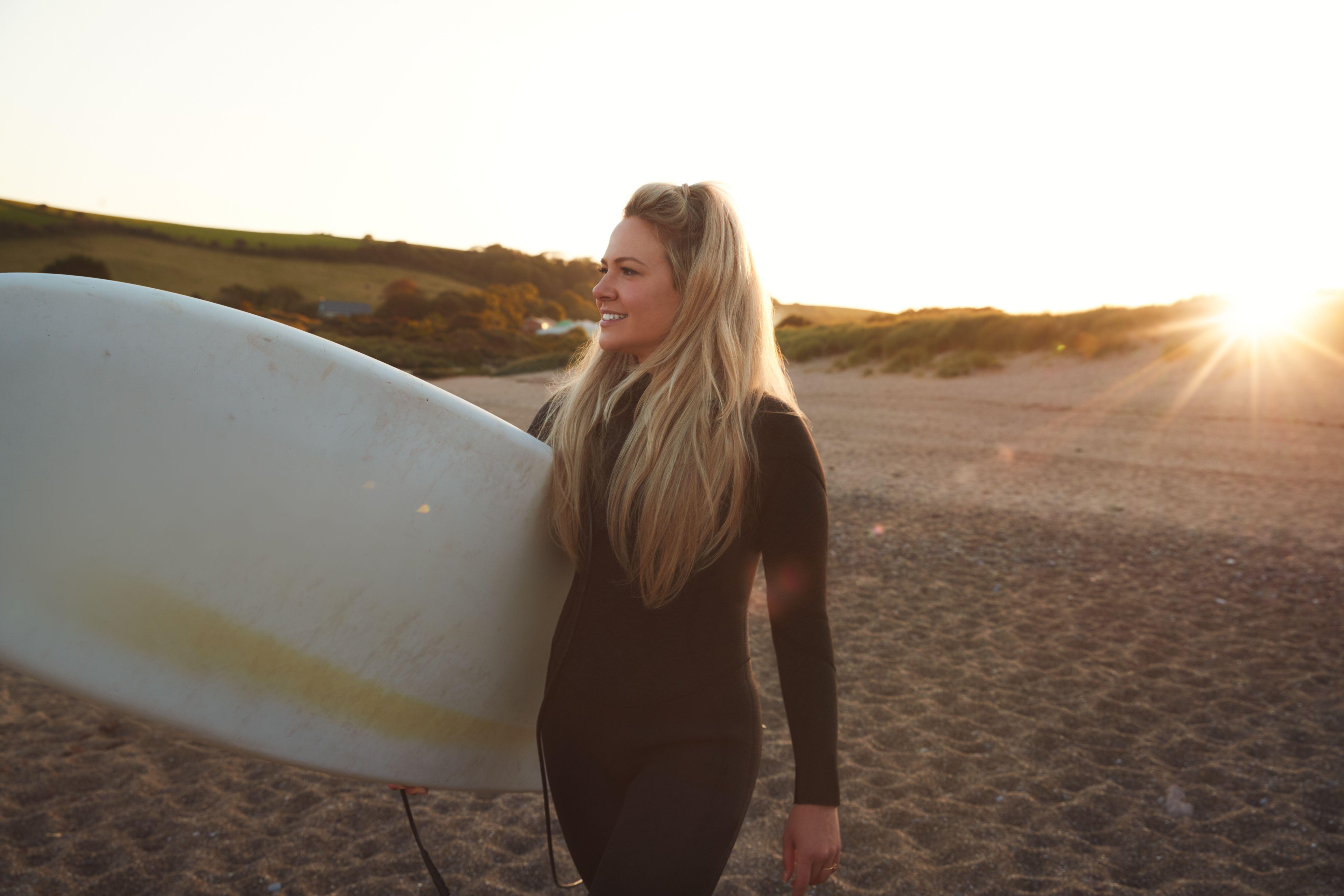 Woman with surfboard on a UK beach