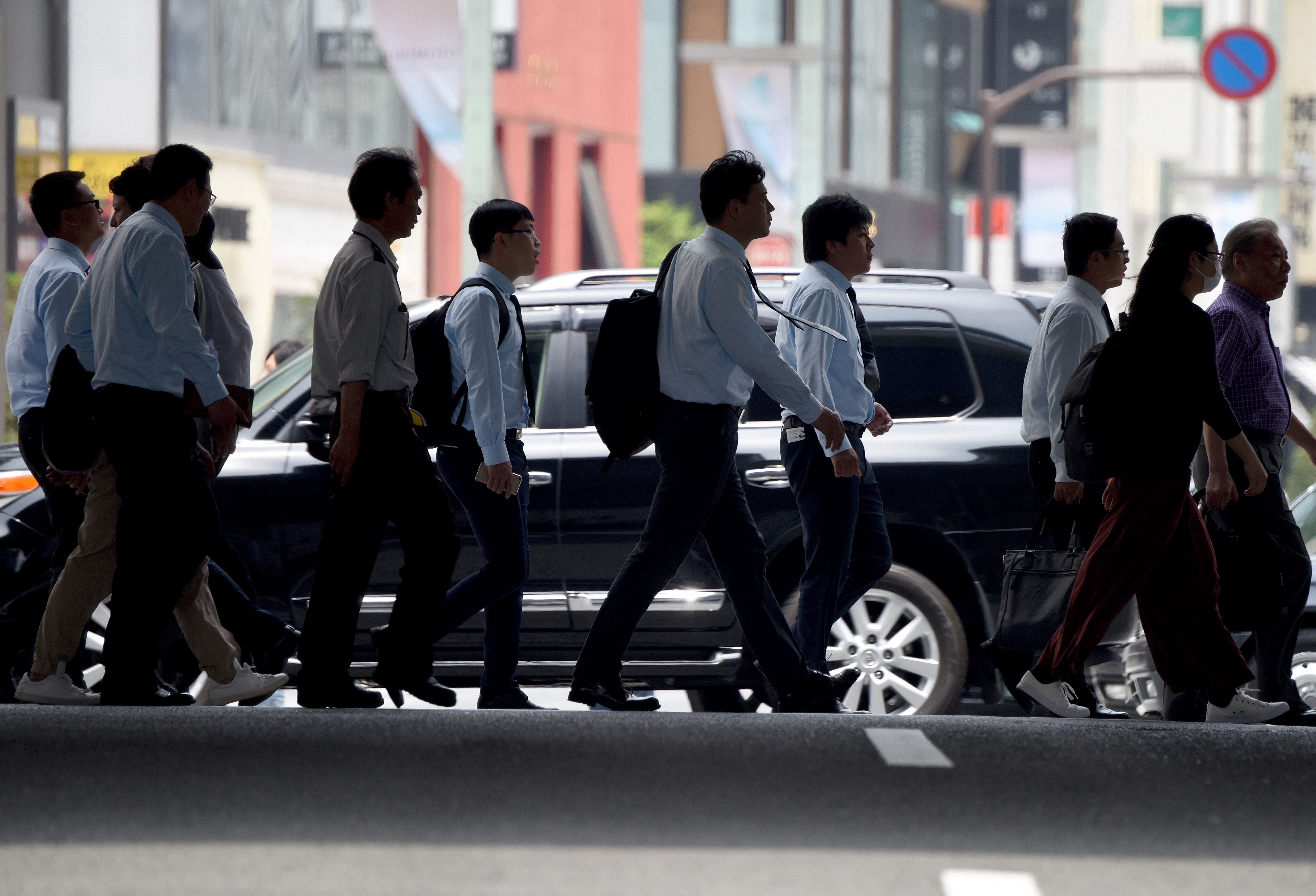 Office workers and pedestrians cross a street in Tokyo on May 31, 2017