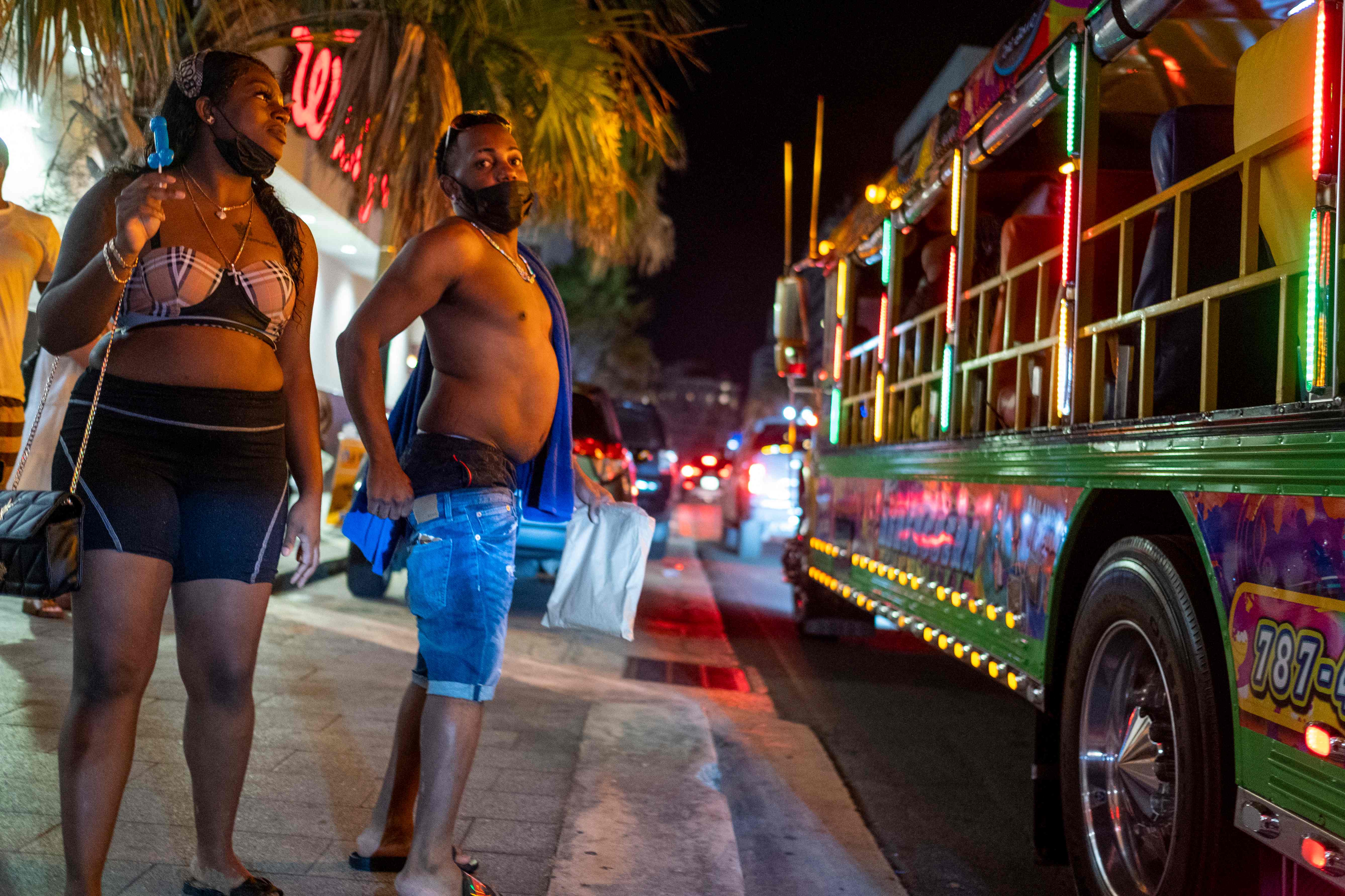 Tourists without face masks stand in front of a party bus in the tourist zone of El Condado in San Juan, Puerto Rico