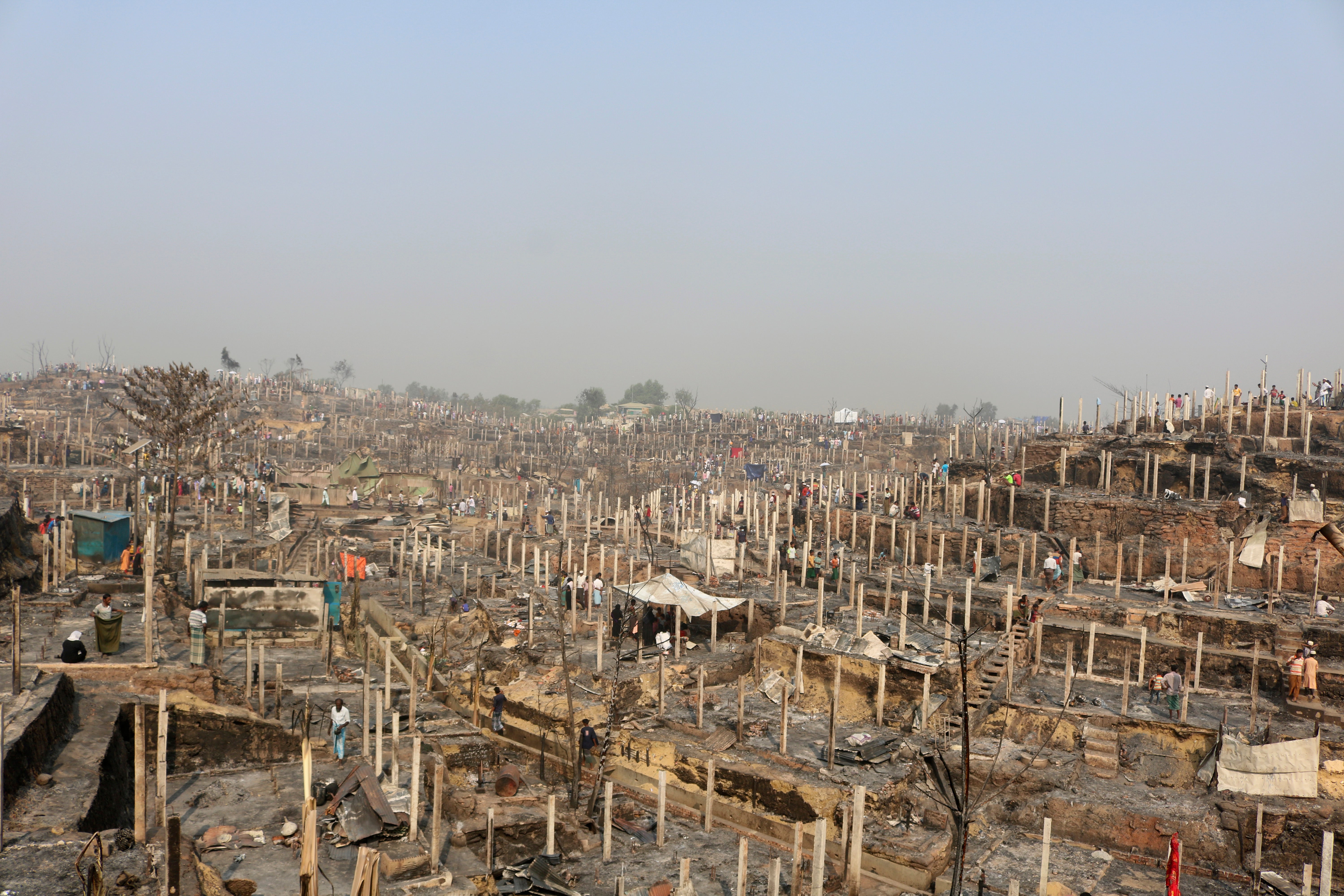 Rohingya refugees stand at the site of Monday's fire at a refugee camp in Balukhali, southern Bangladesh, Tuesday