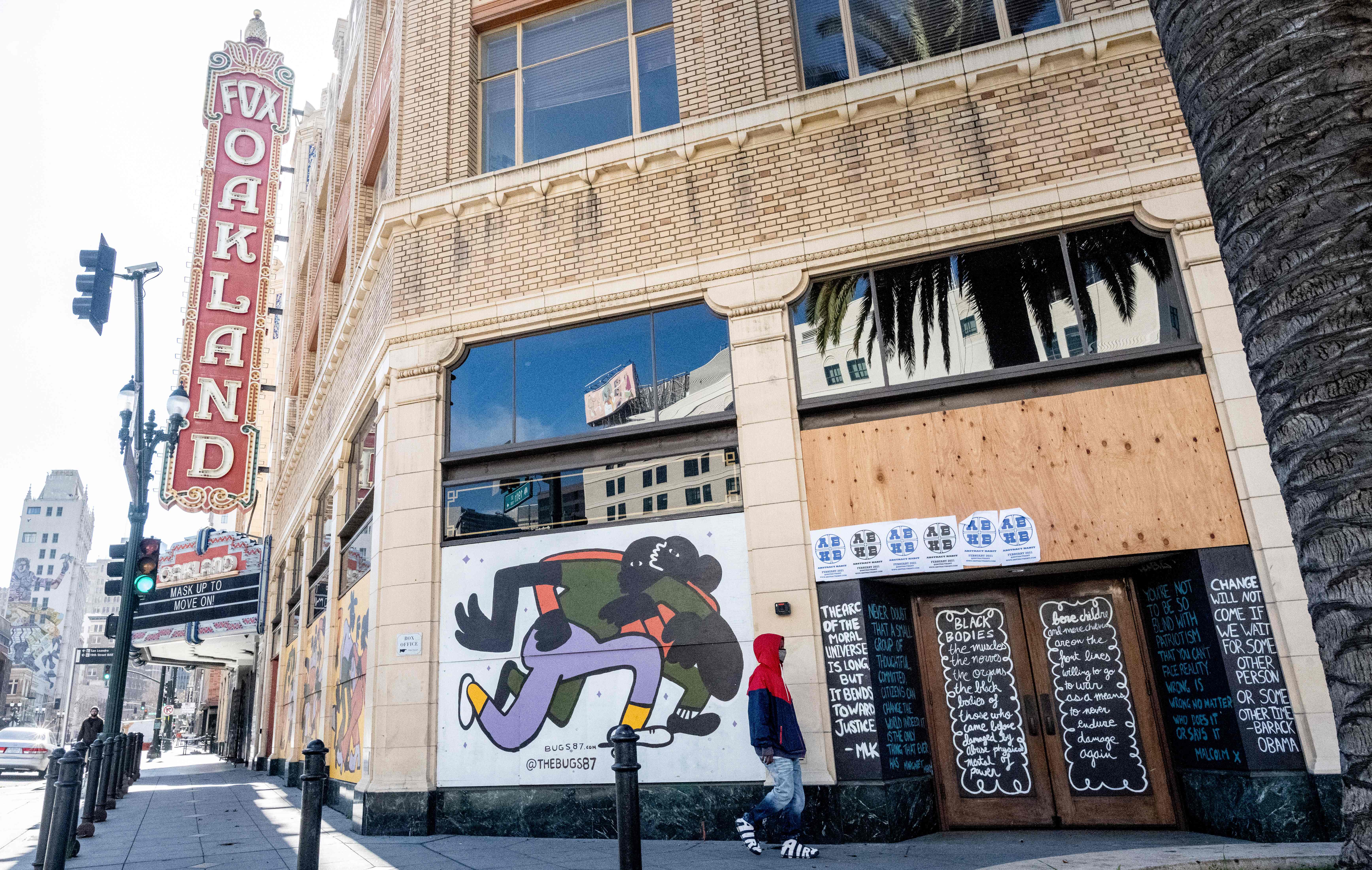 A person walks by a boarded-up shop in Oakland, California on February 12, 2021.