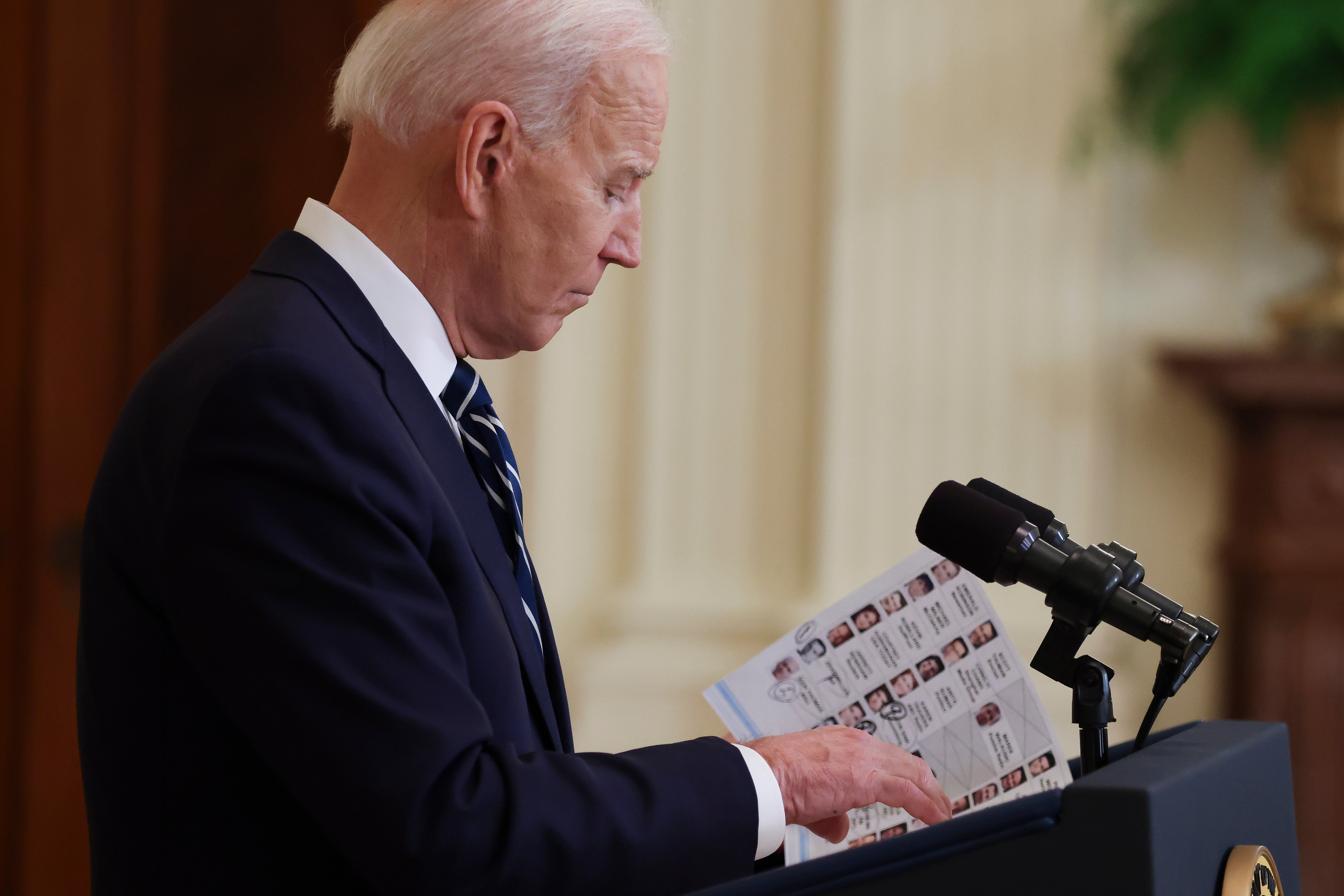 President Joe Biden looks on notes as he answers questions from journalists during the first formal press conference of his presidency in the East Room of the White House