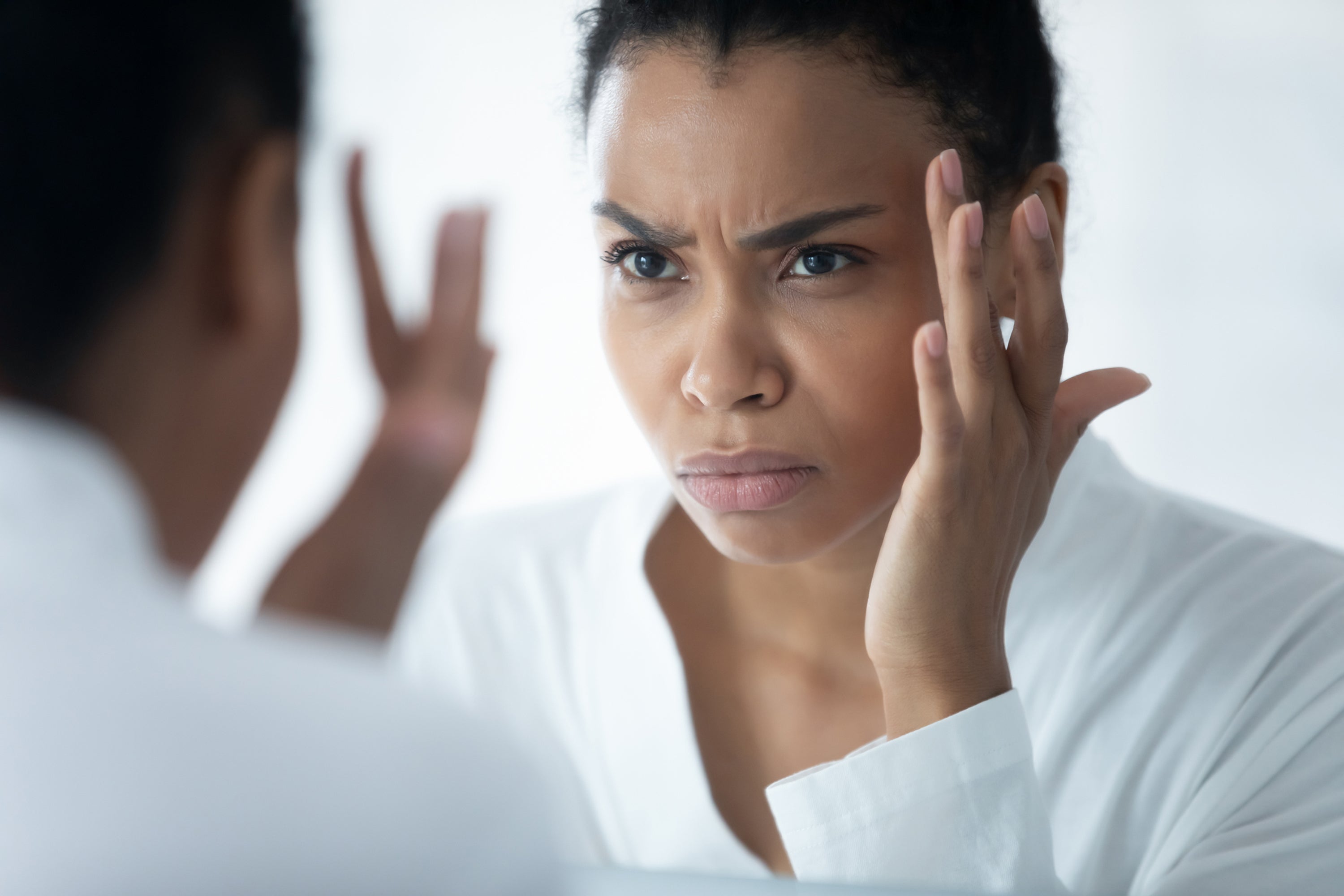 woman examining her skin in the mirror