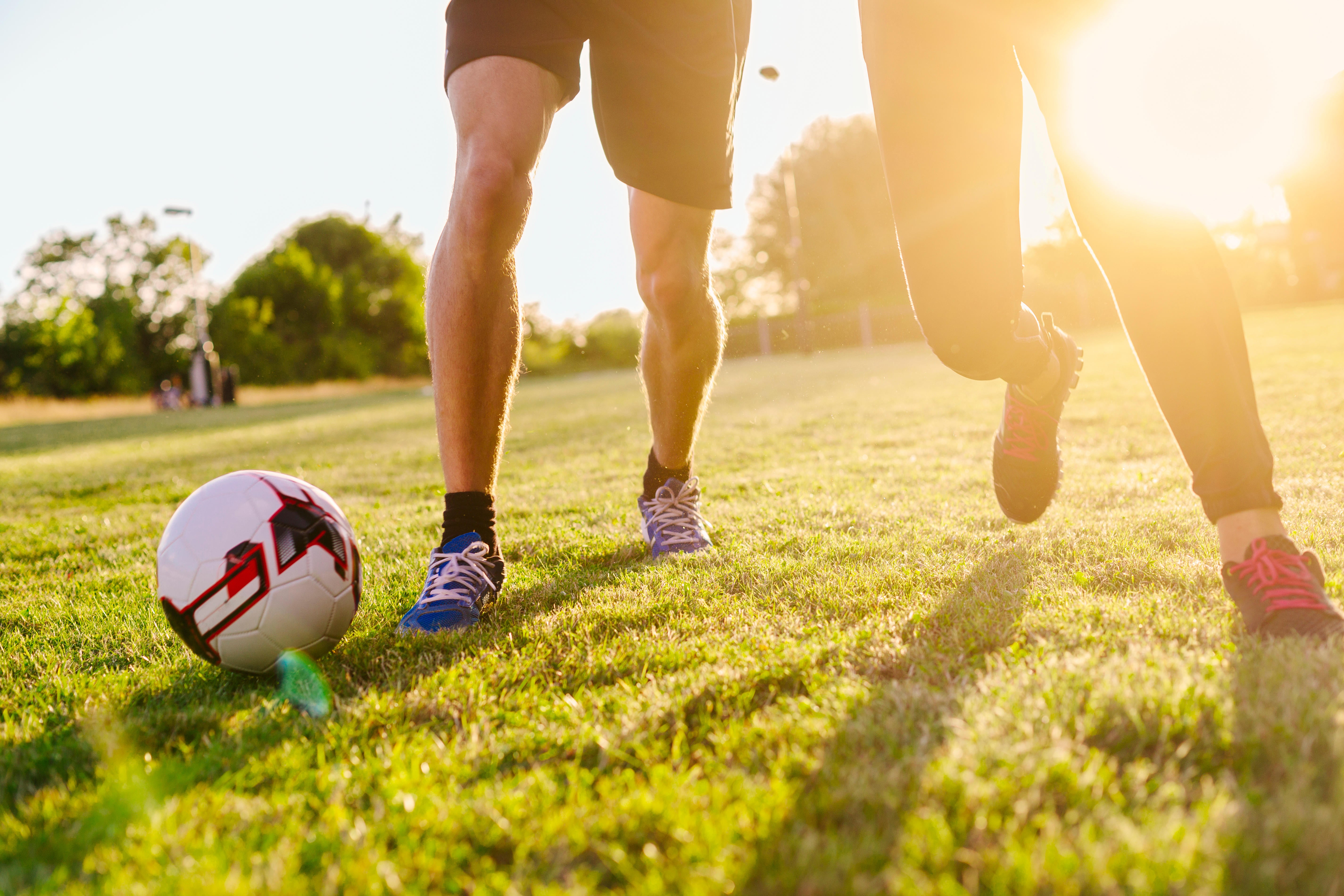 Two people playing football in a park