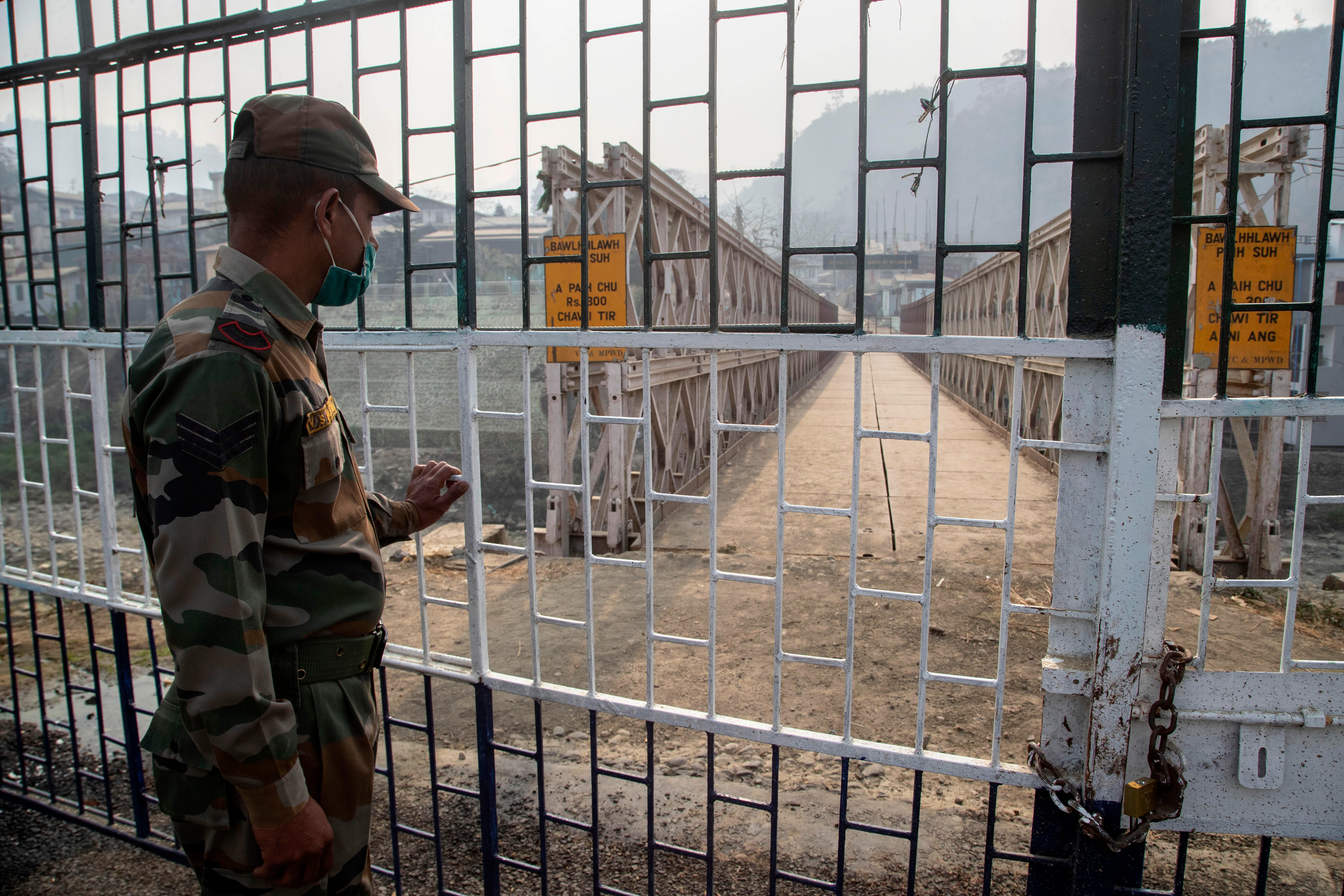 An Indian paramilitary soldier stands guard near the bridge on Tiau river along India-Myanmar border in Mizoram on 20 March, 2021