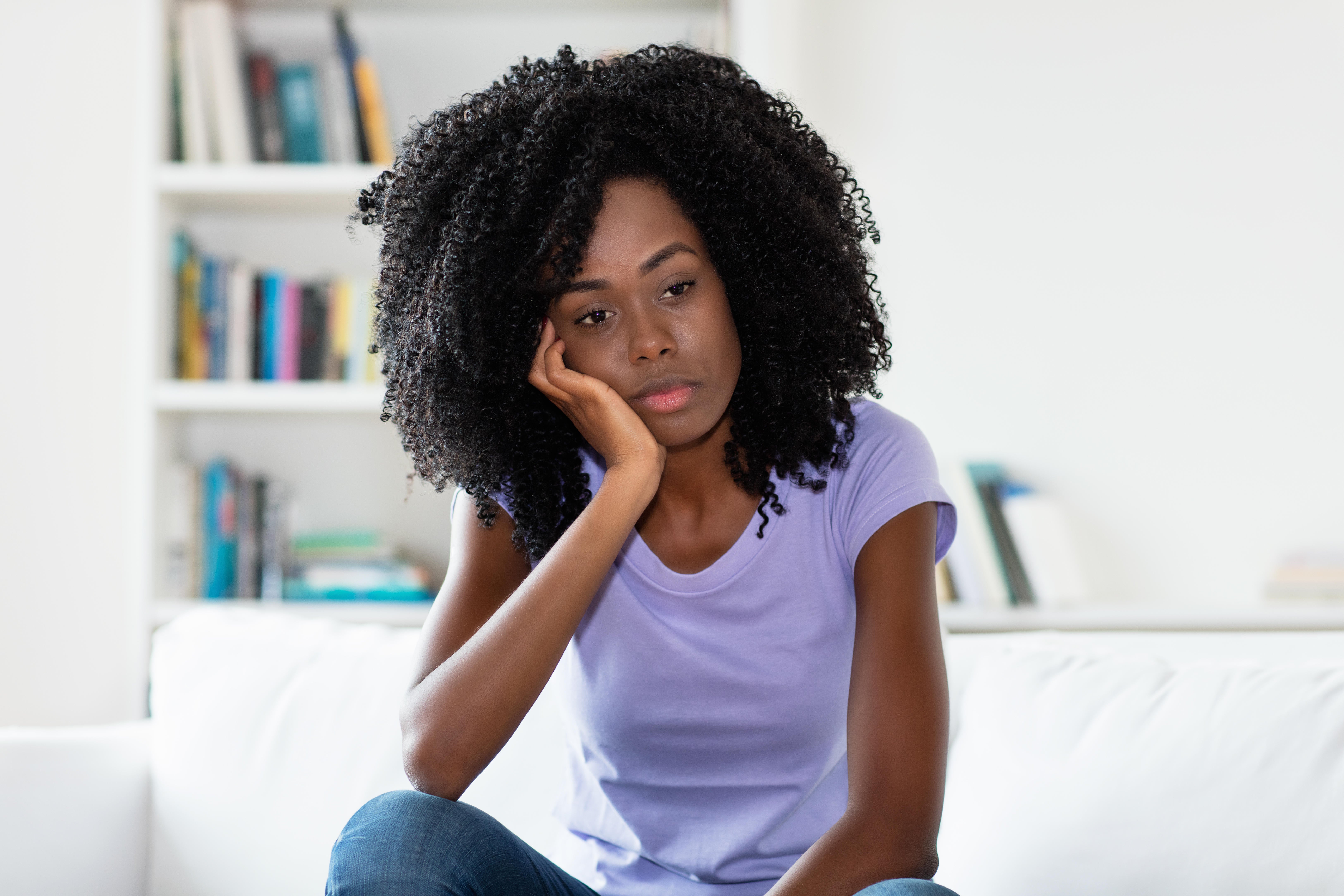 Woman sitting on a sofa at home, deep in thought