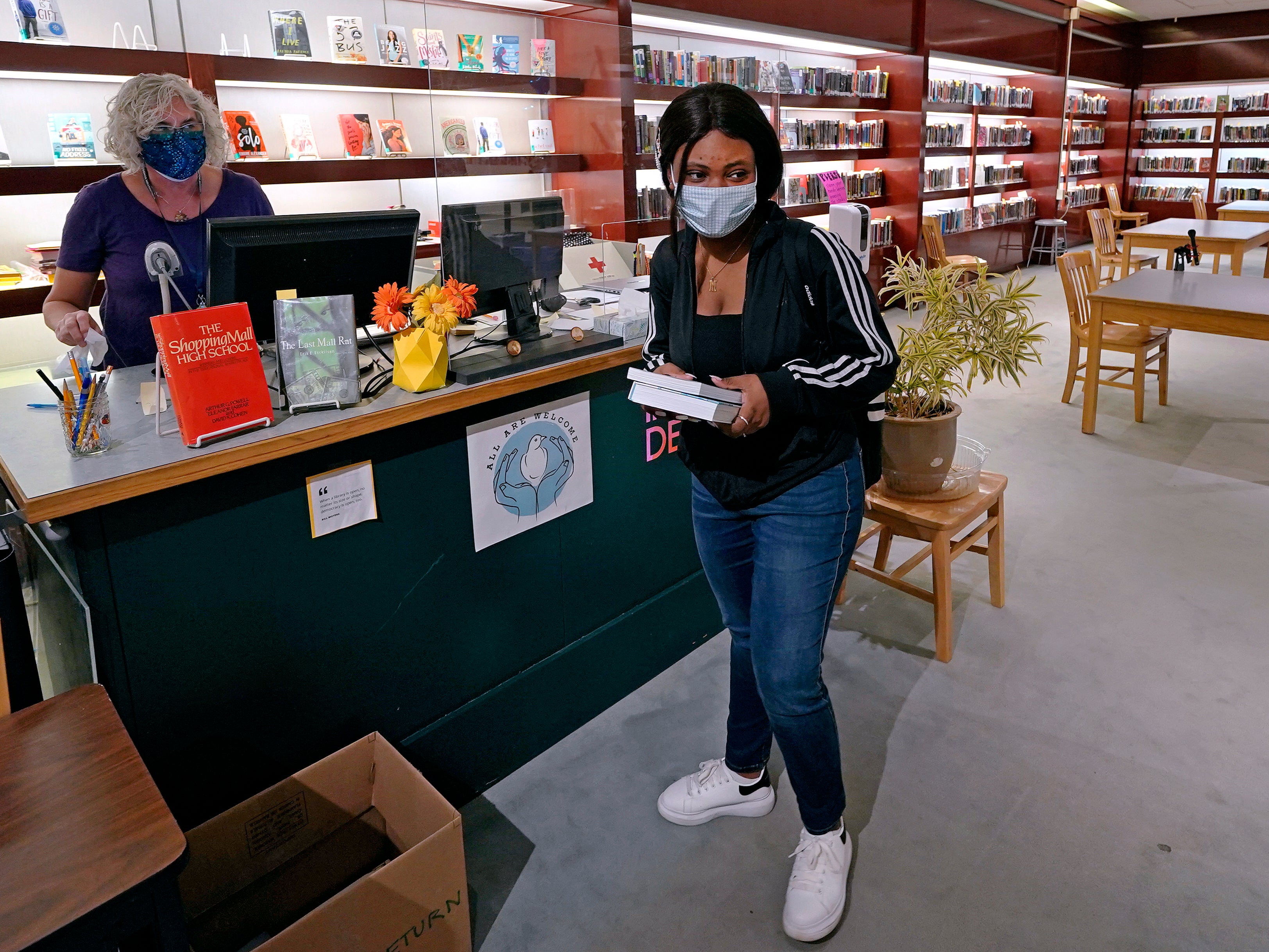 Sophomore Ainerance Babibanga, center, picks up books from the library, which was built in the former china and housewares section of a department store, at Downtown Burlington High School on Monday 22 March, 2021