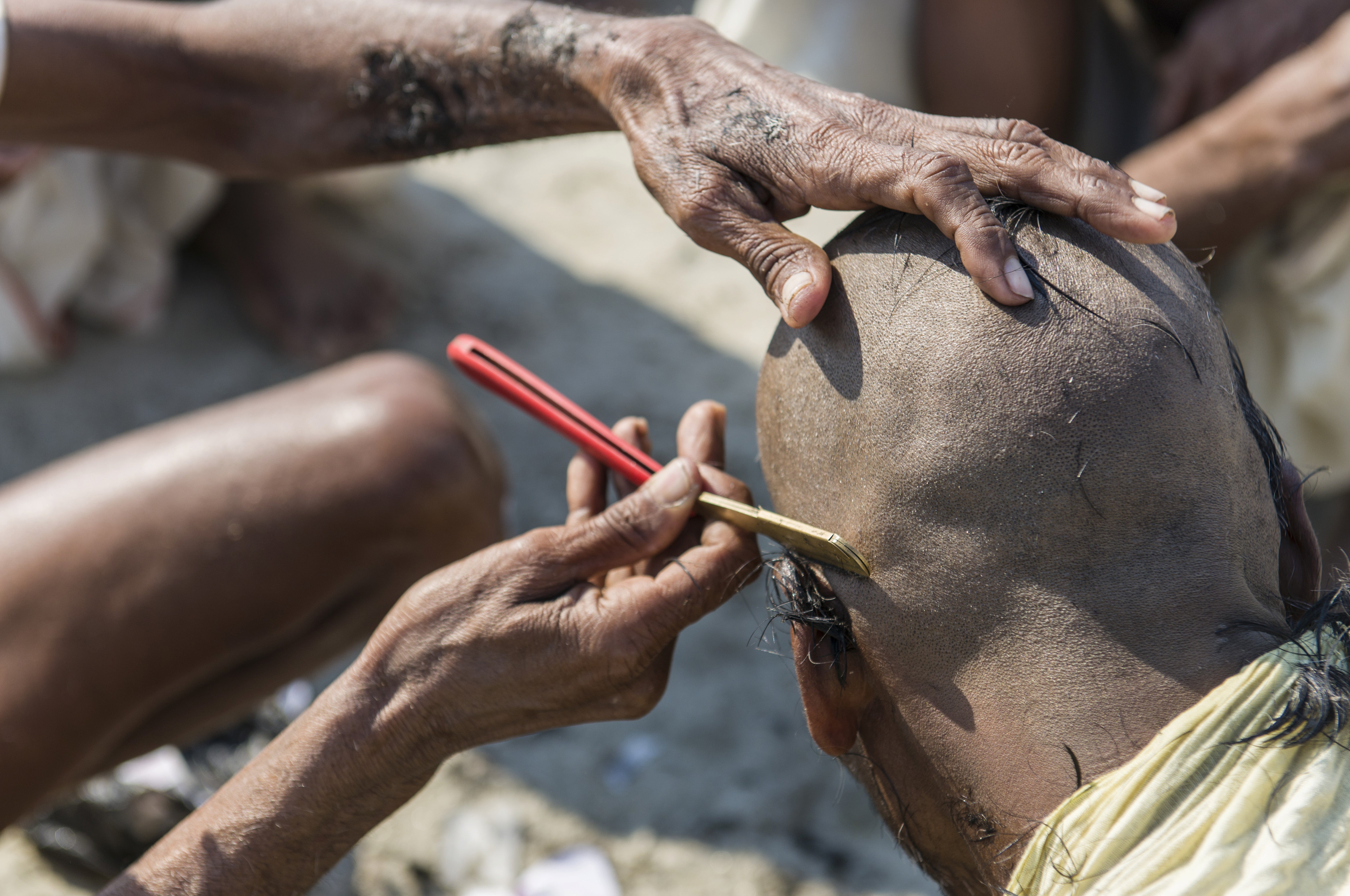 A pilgrim has his head shaved during the Kumbha Mela festival