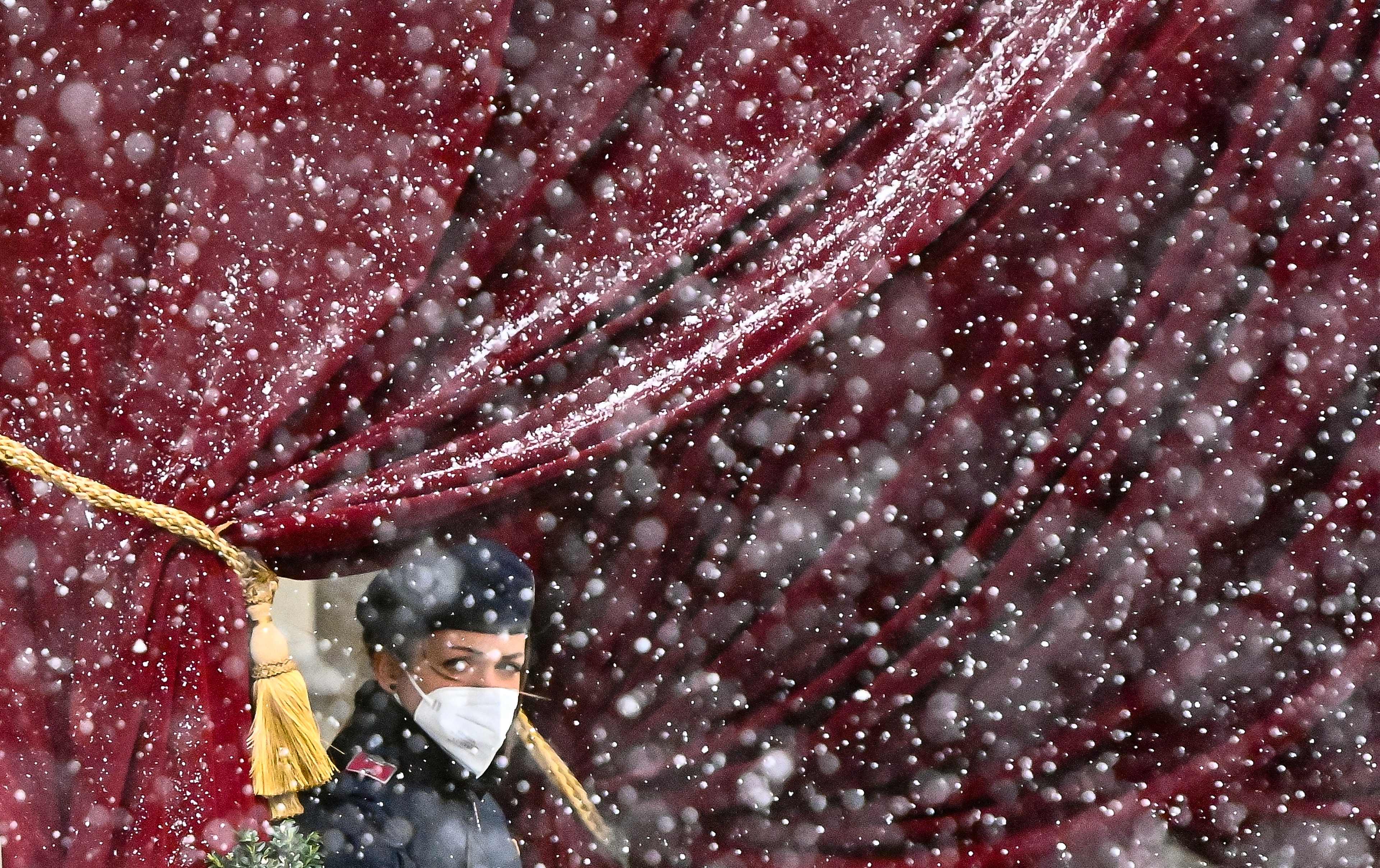 Snow falls as a police officer stands guard near the entrance of the Grand Hotel in Vienna on April 6, 2021, where diplomats of the EU, China, Russia and Iran will hold talks