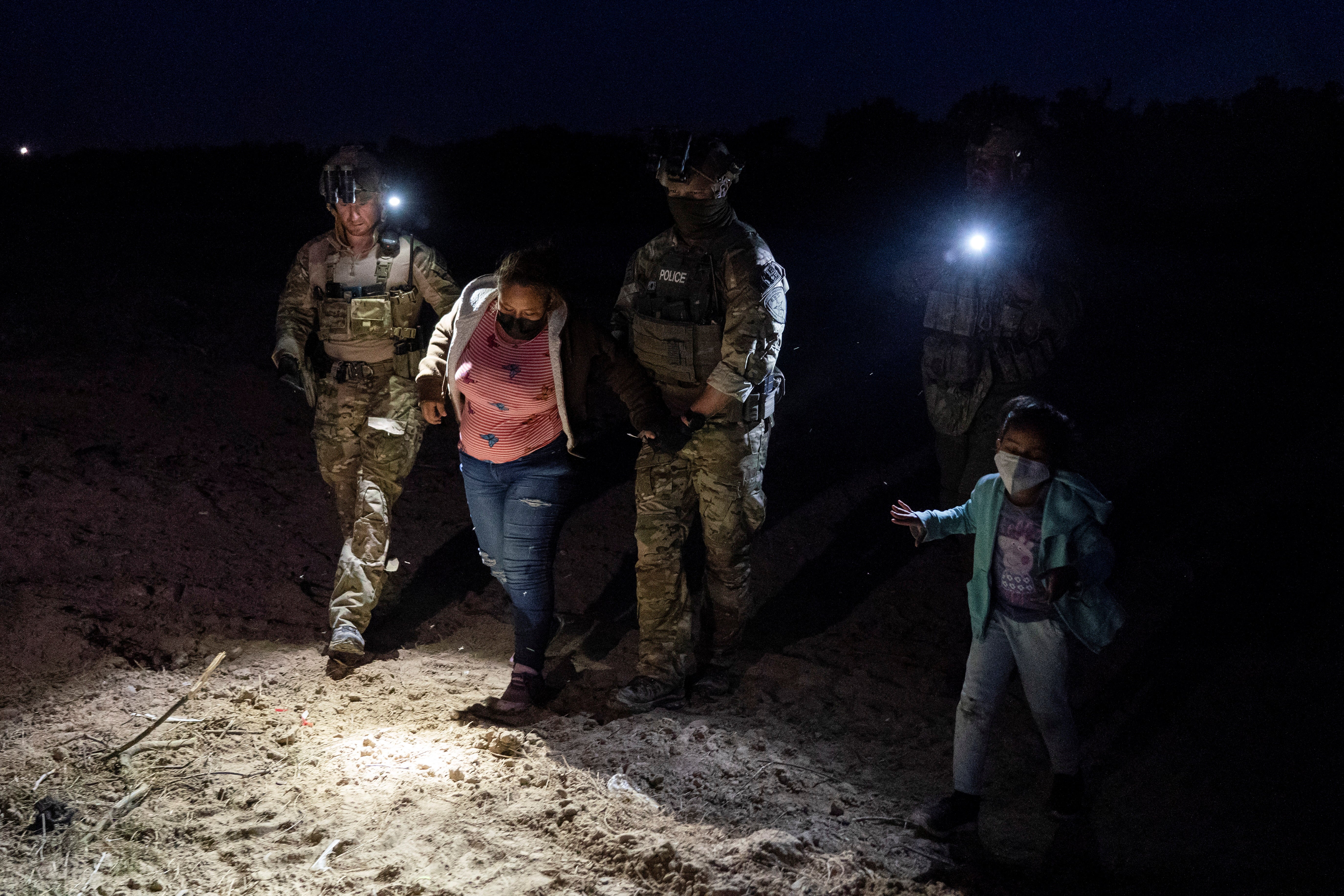 Texas rangers pick up a migrant woman after she crosses the Rio Grande