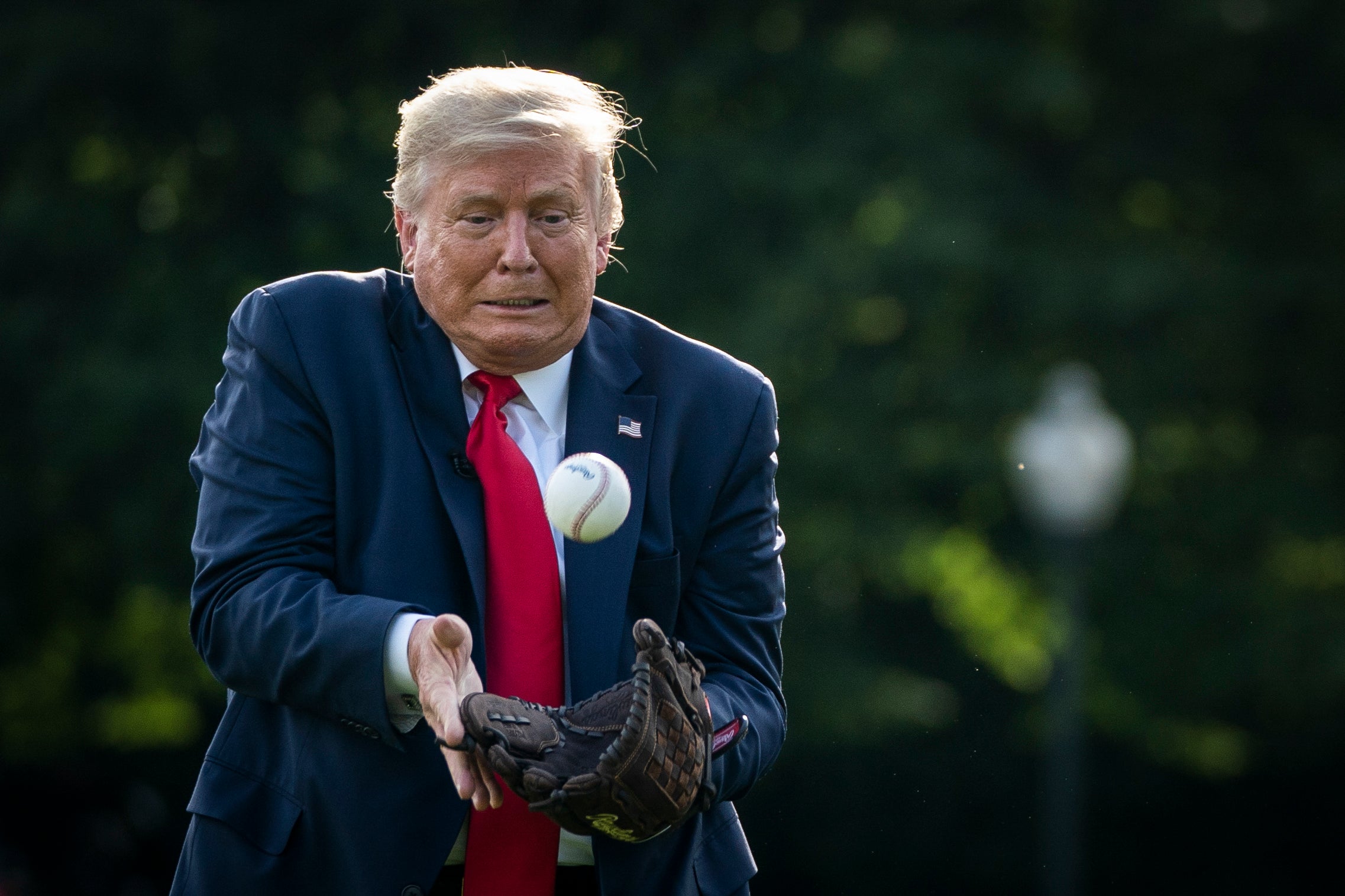 Donald Trump tries to catch a baseball thrown by former New York Yankees Hall of Fame pitcher Mariano Rivera on the South Lawn of the White House on July 23, 2020