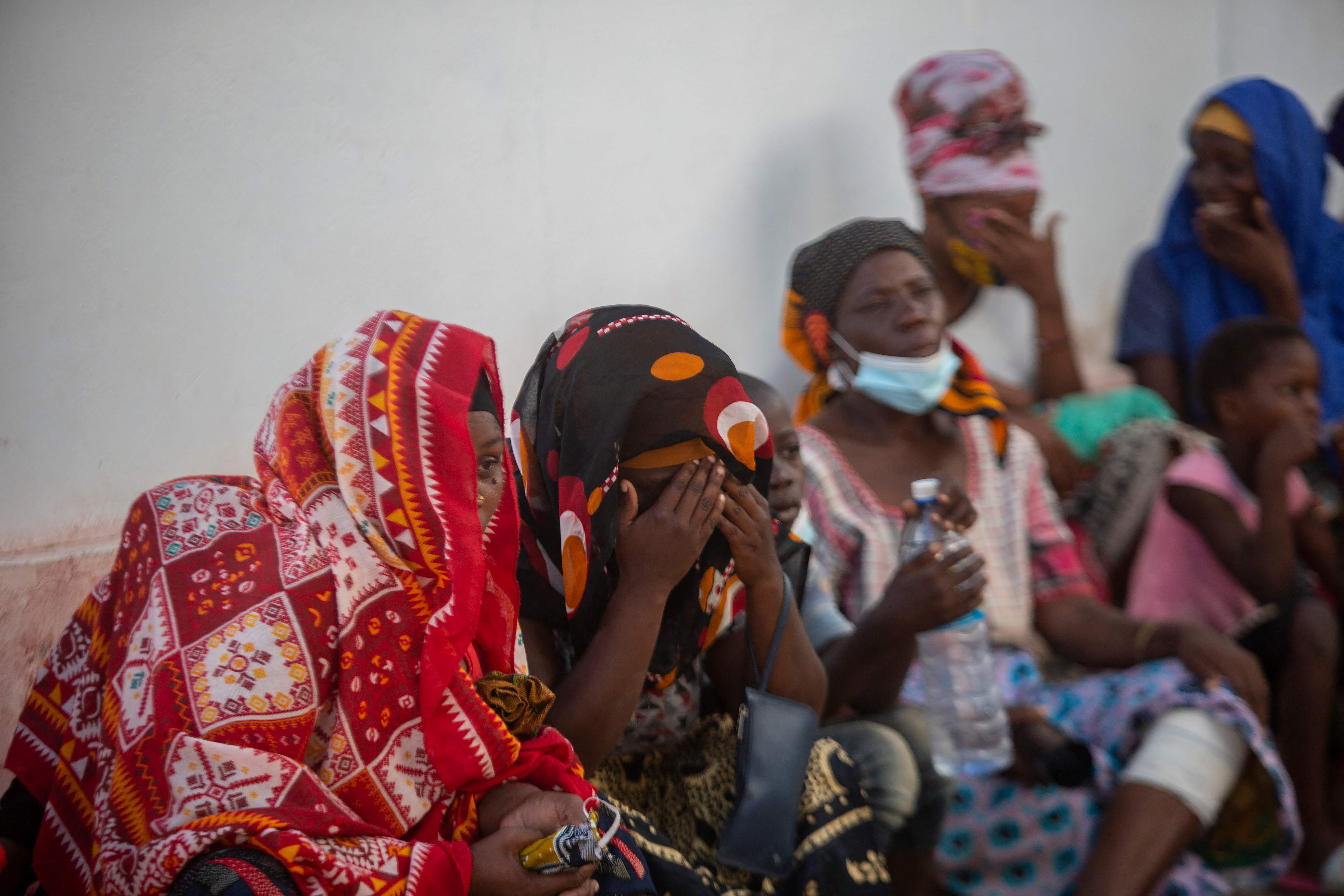 People on the outskirts of the sea port of Pemba await a boat carrying their relatives evacuated from the coasts of Afungi and Palma