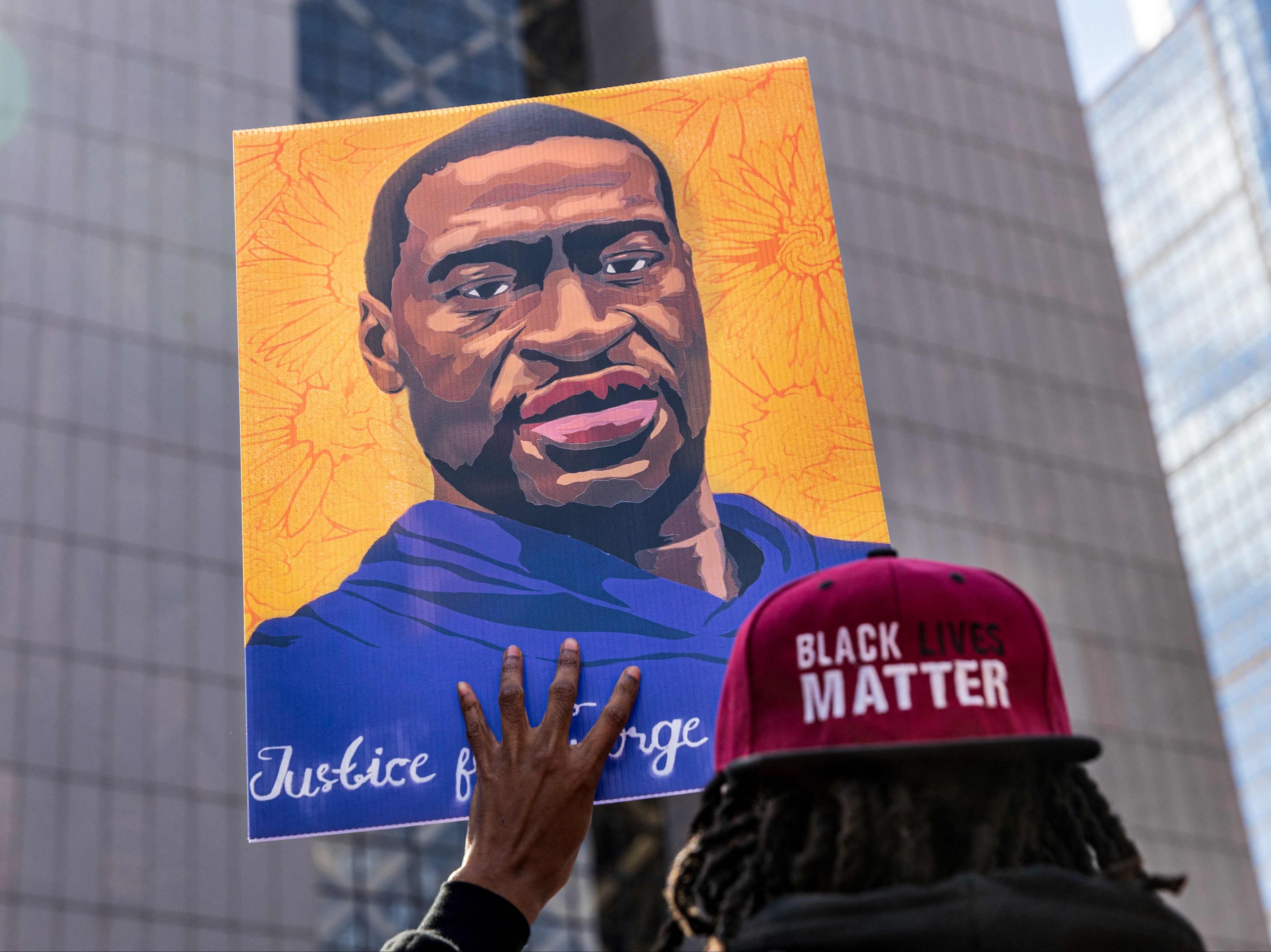 Demonstrators hold signs honouring George Floyd and other victims of racism as they gather during a protest outside Hennepin County Government Centre on 28 March 2021 in Minneapolis, Minnesota