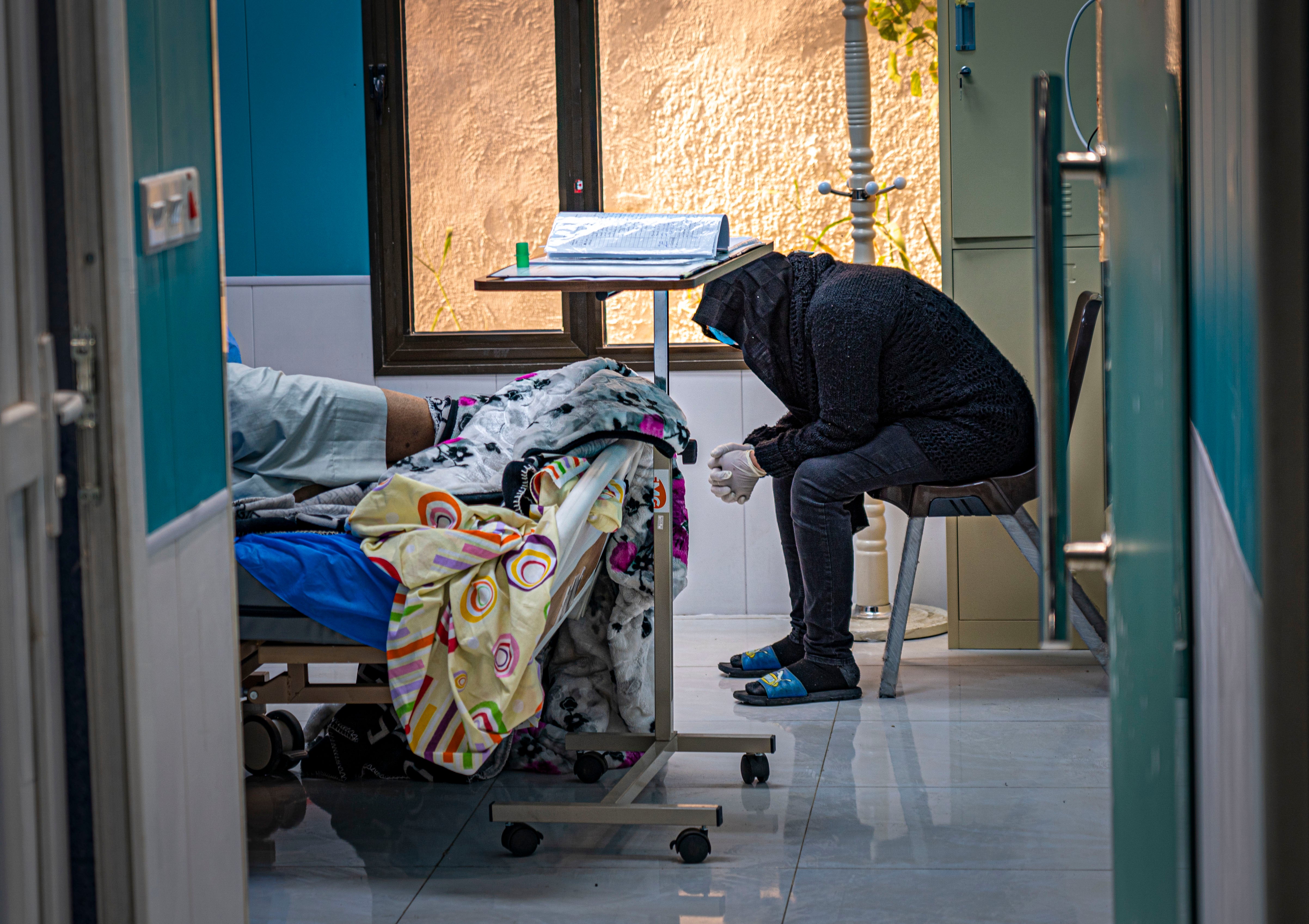 A woman anxiously waits for news on her critically ill husband’s condition