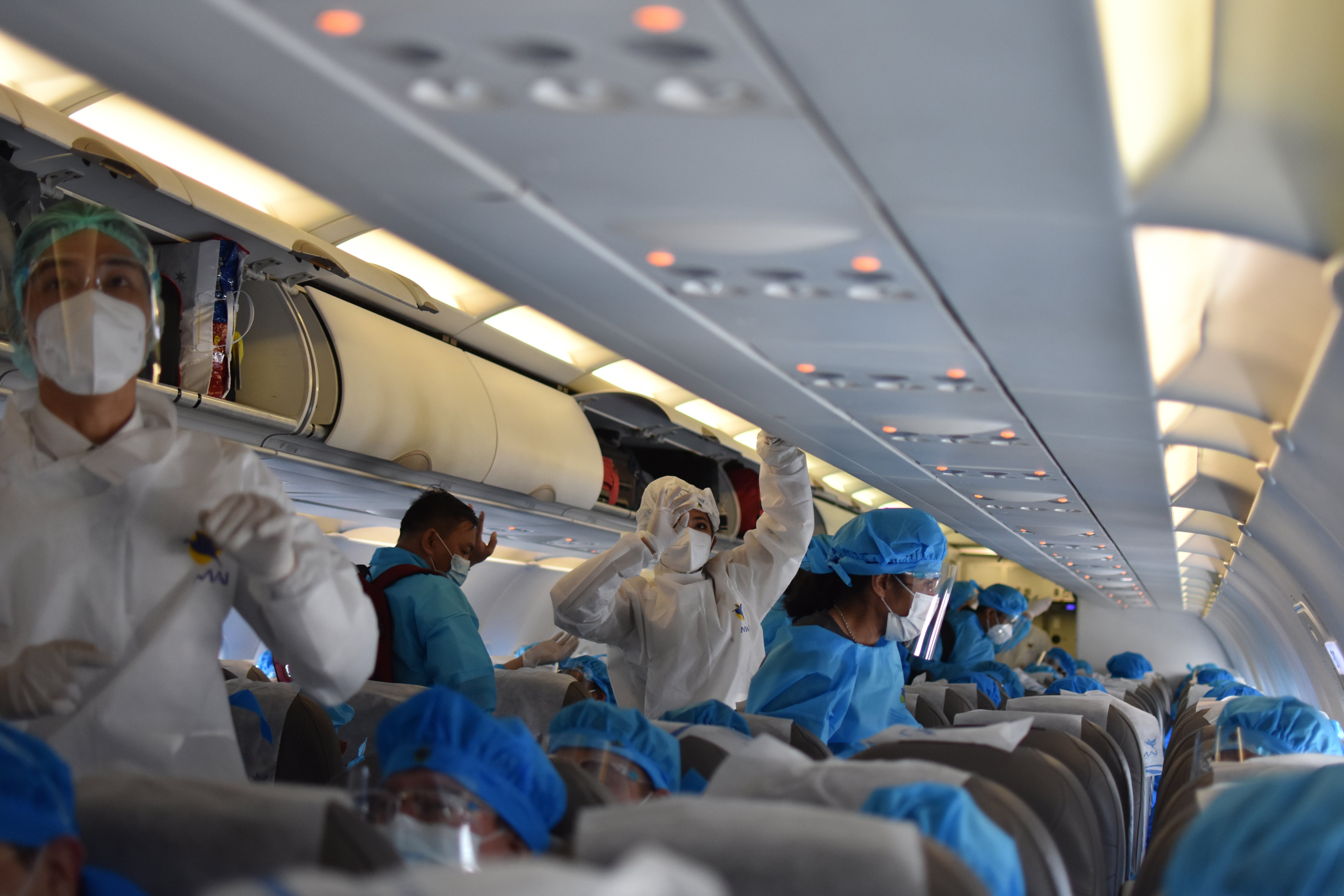 Passengers in coronavirus gear provided by the airline board a relief flight from Seoul to Yangon