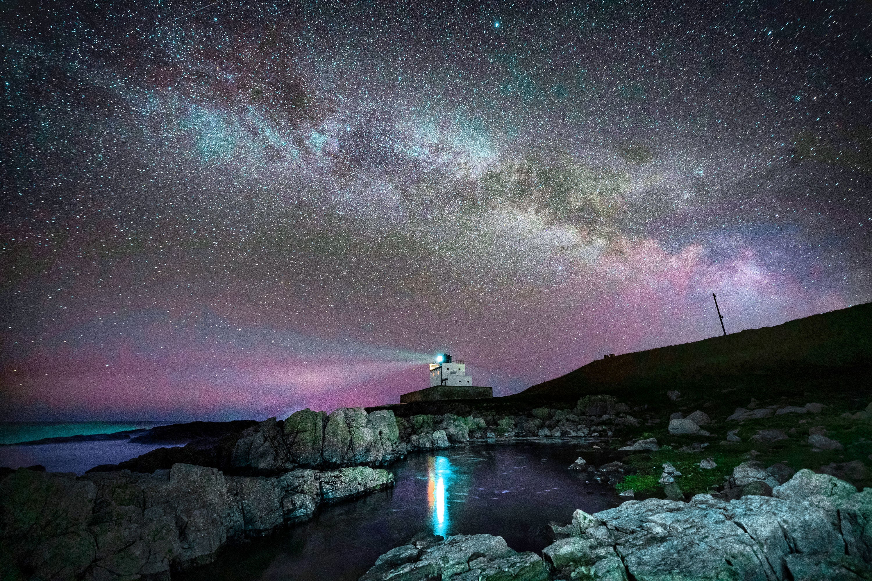 The core of the Milky Way becomes visible in the early hours of Tuesday morning as it moves over Bamburgh Lighthouse at stag Rock in Northumberland