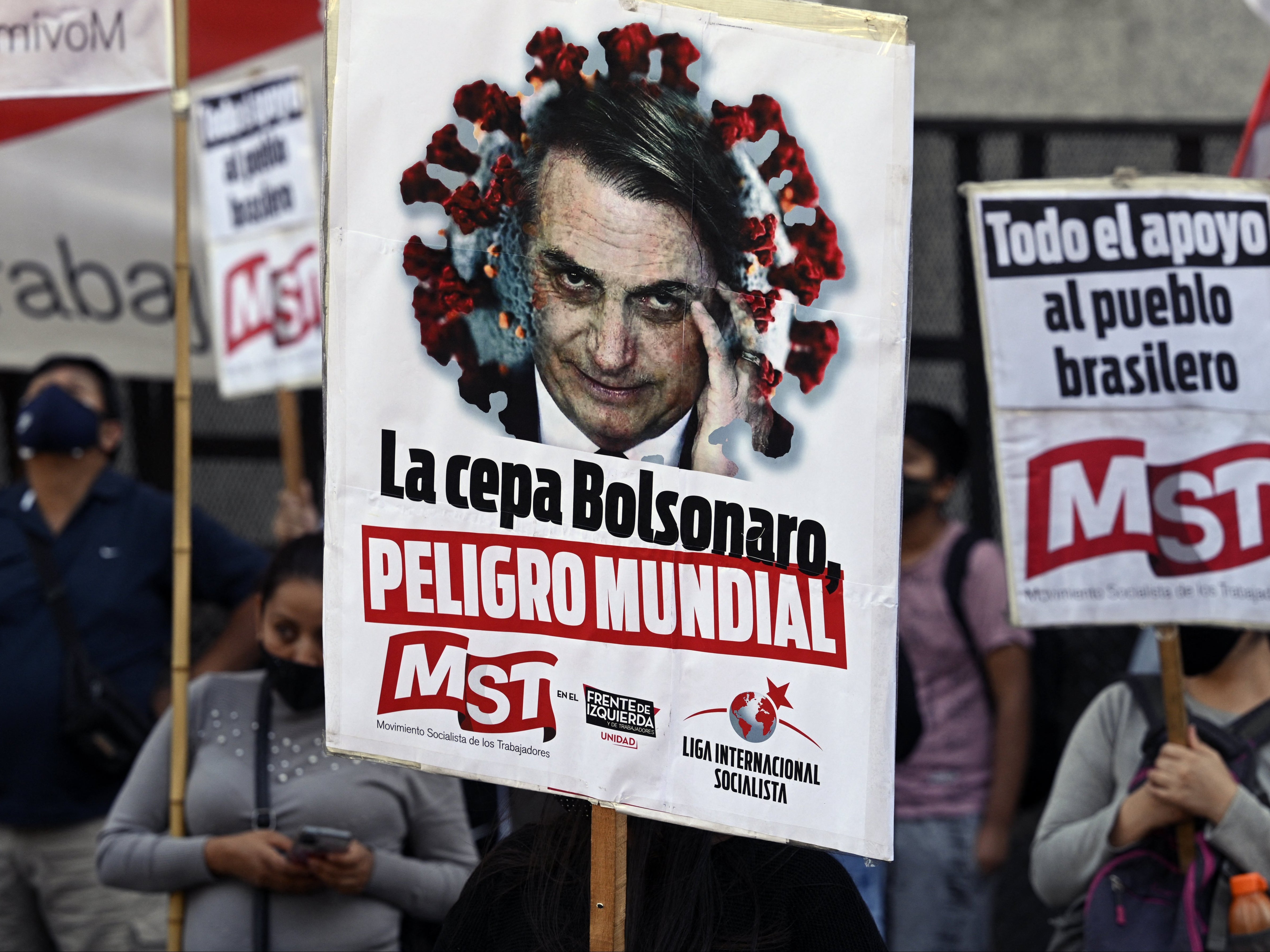 People hold banners depicting Brazilian president Jair Bolsonado reading ‘The Bolsonaro strain, world danger’ during a protest at the Brazilian embassy in Buenos Aires on Wednesday