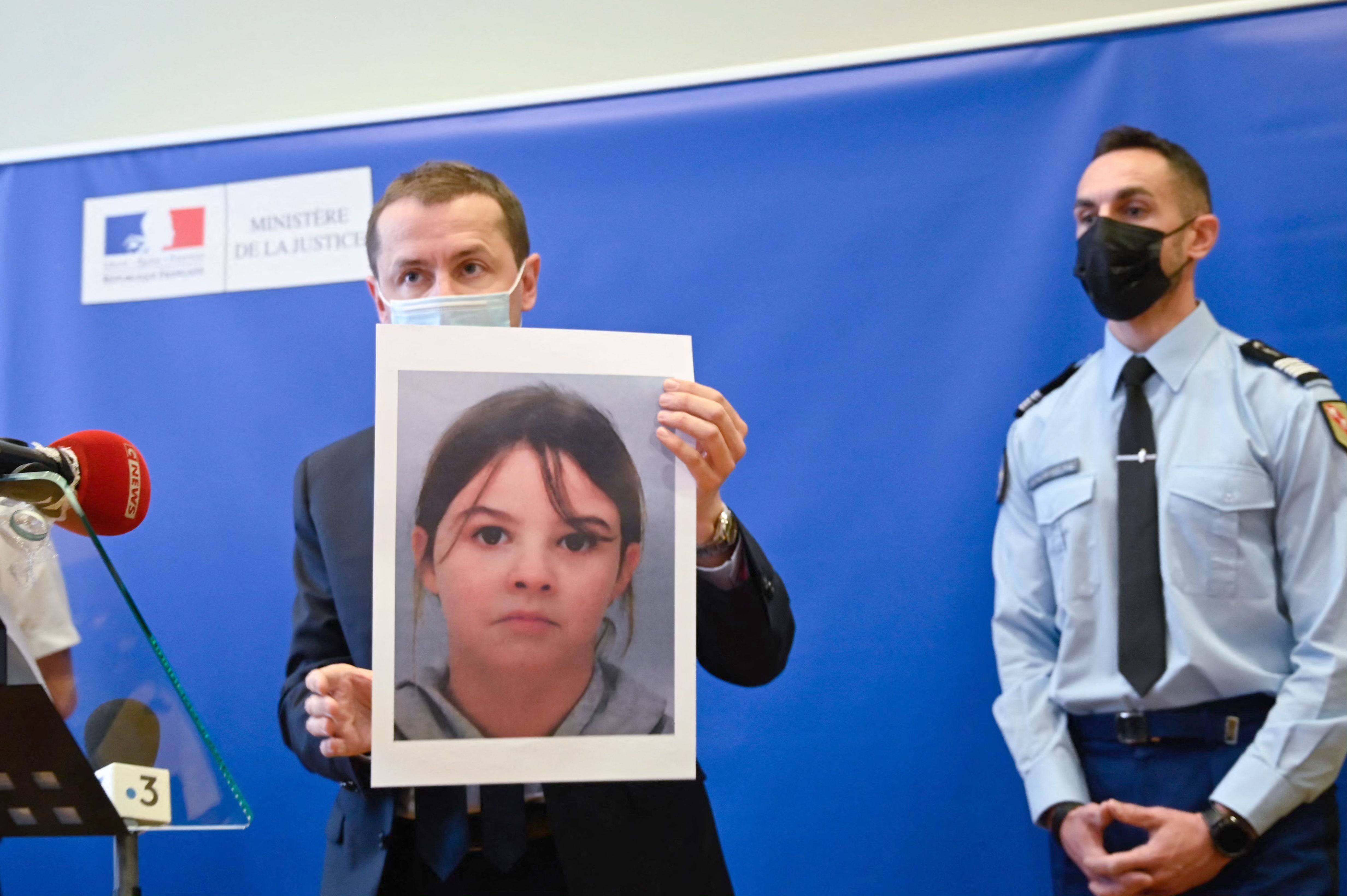 French public prosecutor Nicolas Heitz (C) holds a portrait of missing child Mia Montemaggi