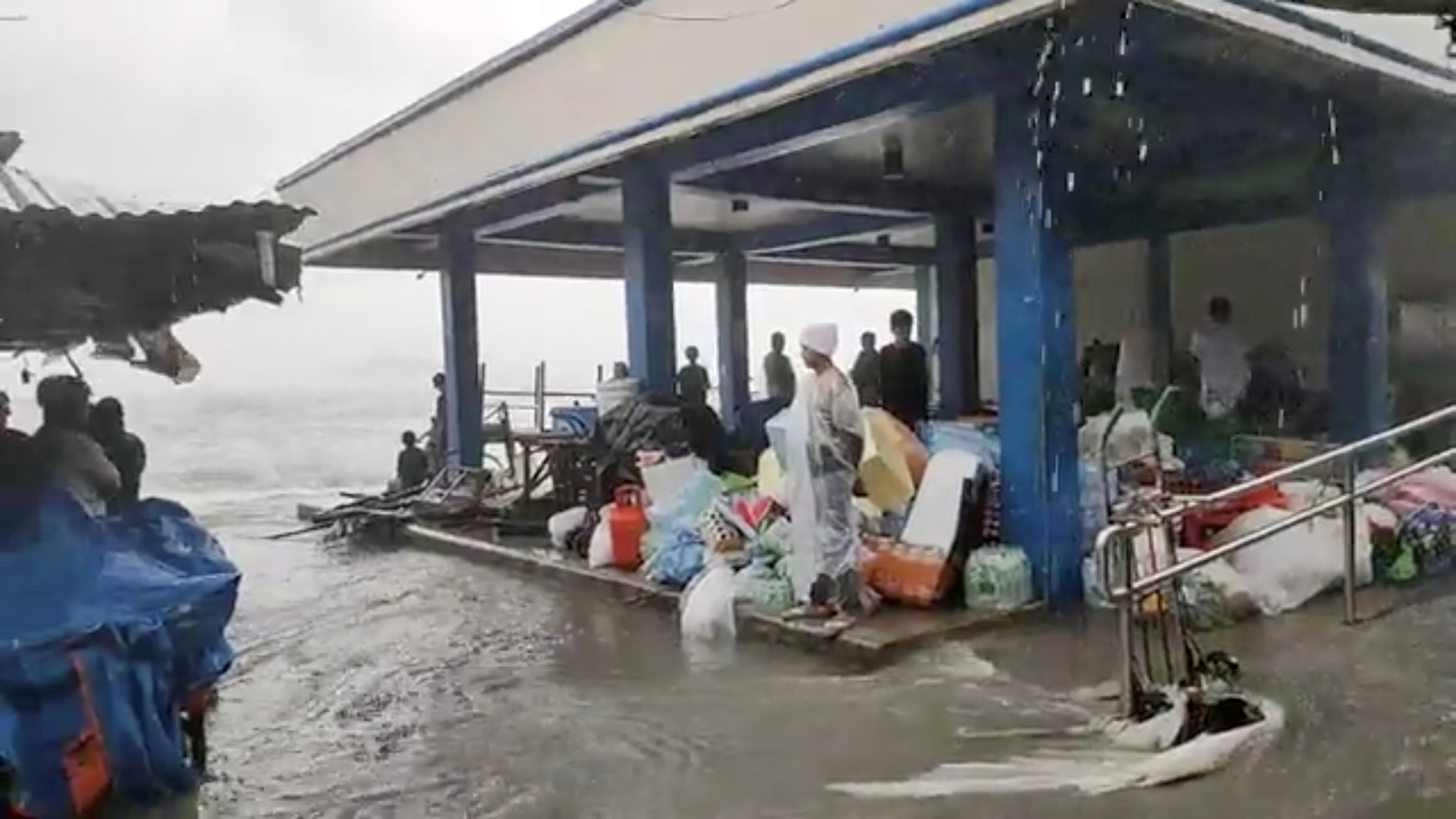 People stand in cover on a flooded market as Super Typhoon Surigae moves close to the Philippines in the province of Catbalogan