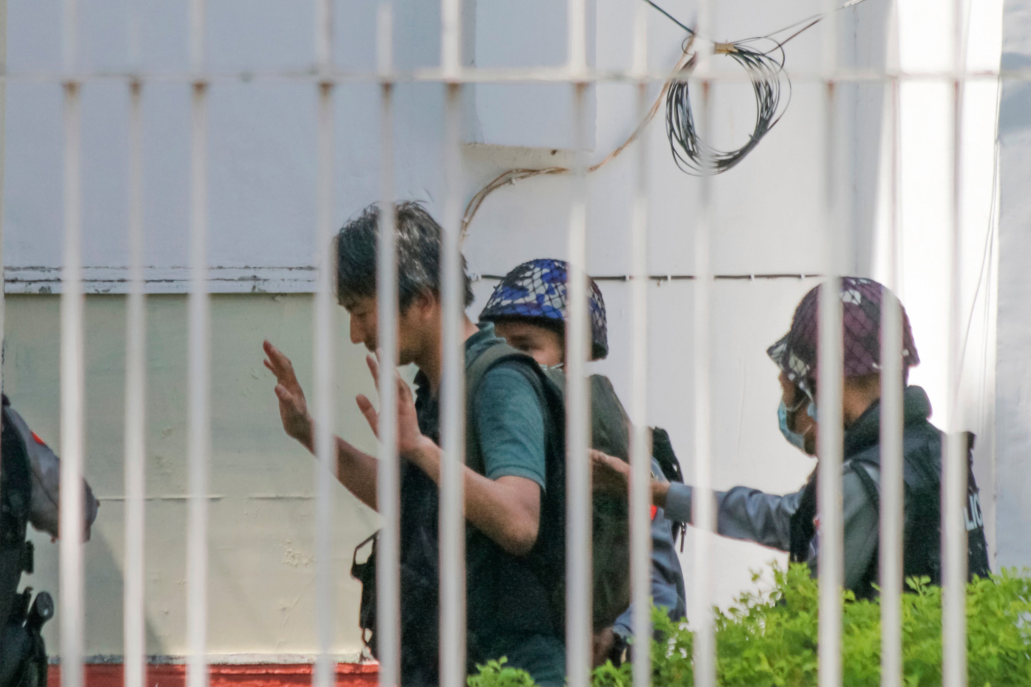 Japanese journalist Yuki Kitazumi in this 26 February photo raises his hands as he is escorted by police in Yangon, Myanmar.