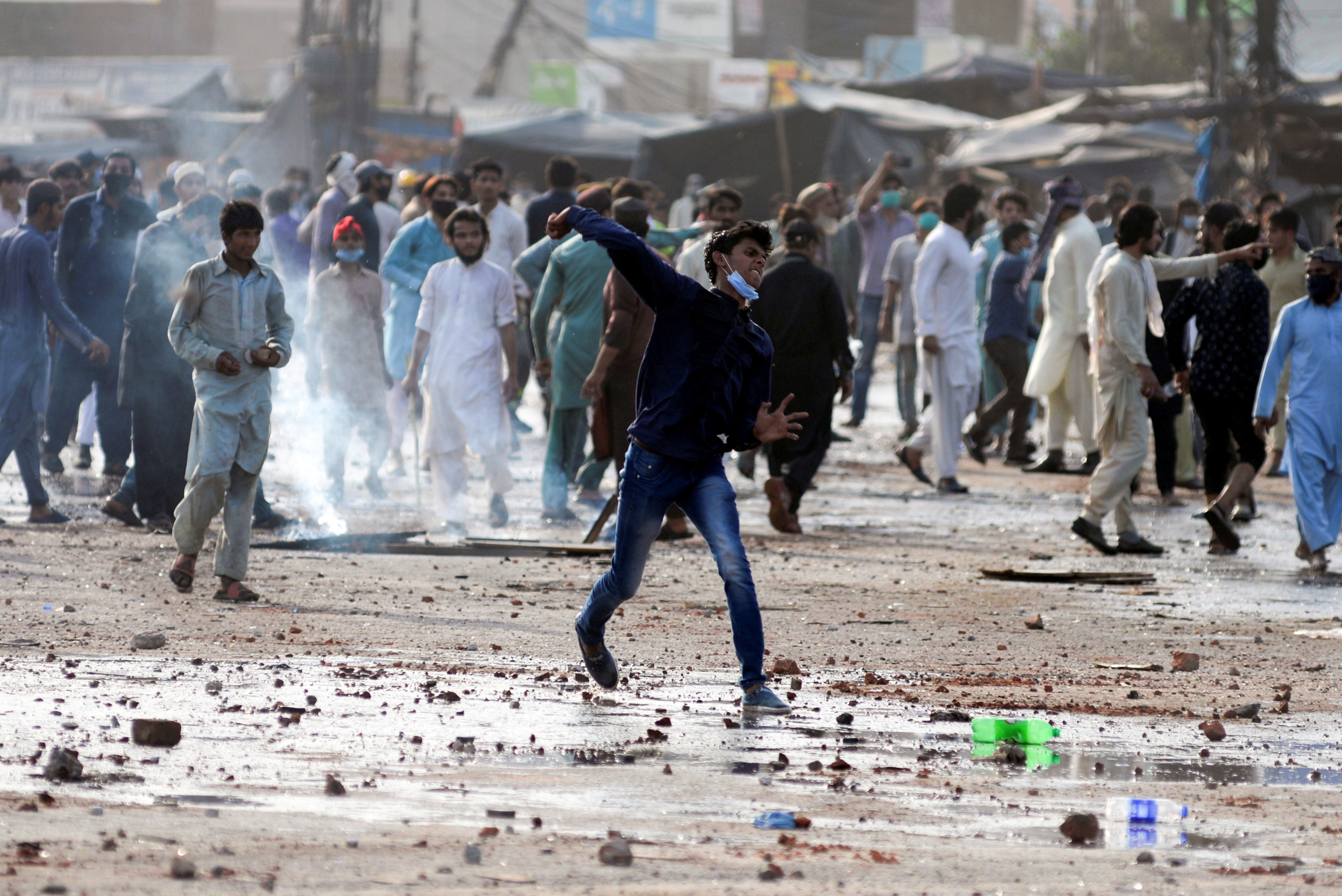 An anti-French protester hurls stones towards police during a protest in Lahore, Pakistan