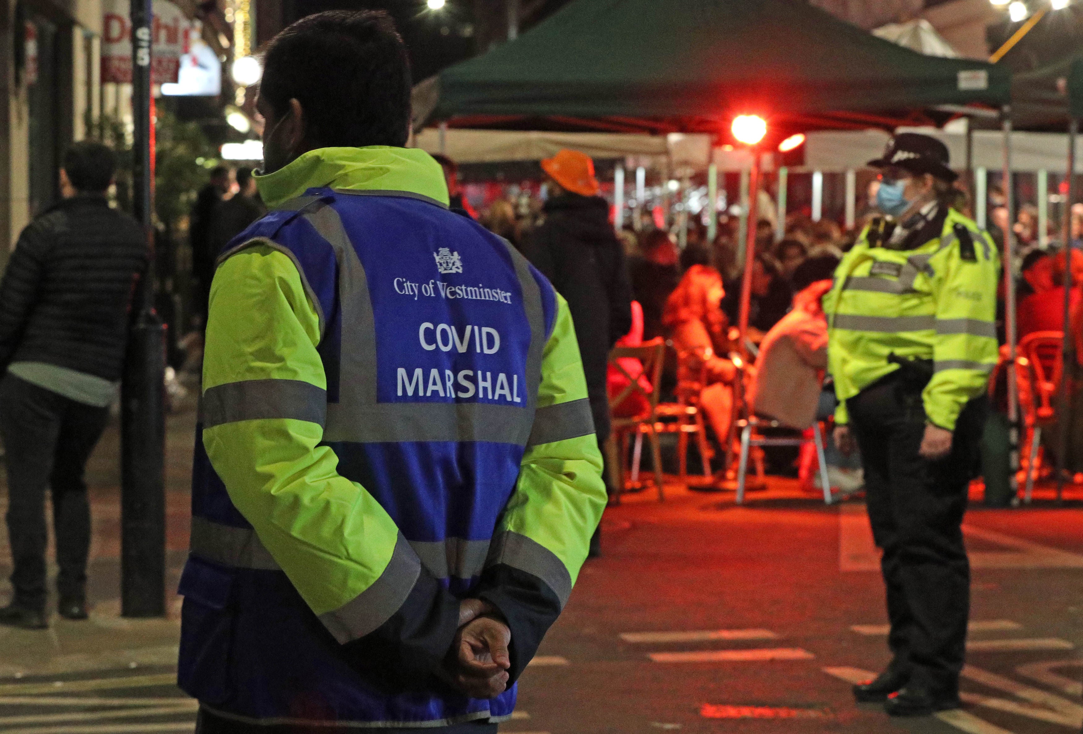 A Covid Marshal and Police Officer at the junction between Frith Street and Old Compton Street in Soho, London