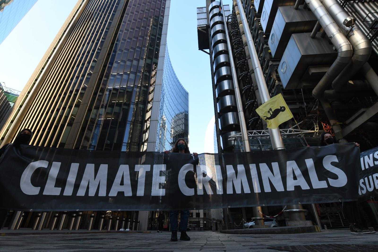 An activist stands next to a ‘climate criminals’ banner outside Lloyd’s