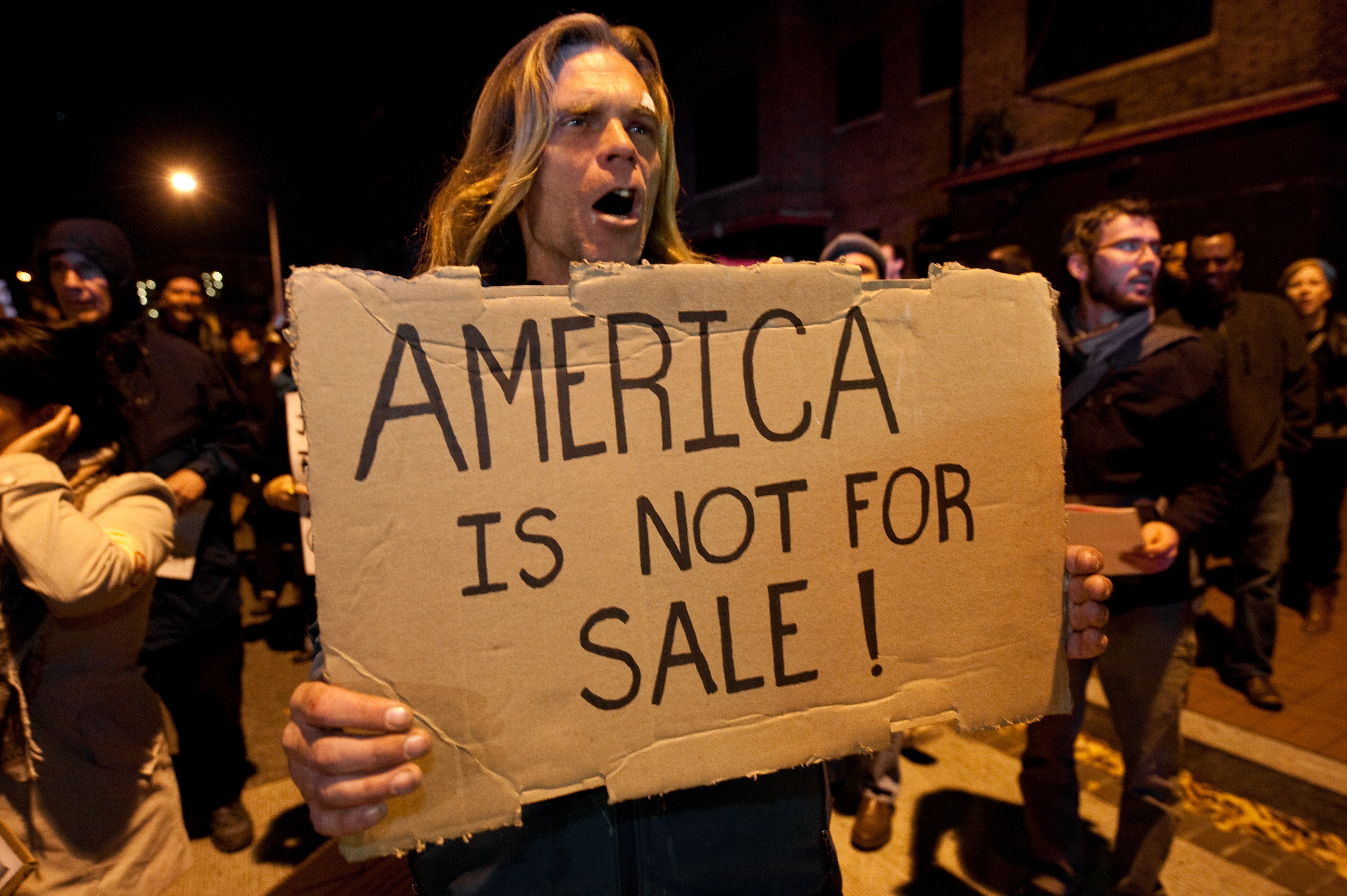 Congress has been urged to act to stop billionaire donors after new analysis found that 12 people contributed $3.4billion to federal campaigns in the last ten years. Pictured a protestor from the Occupy DC march in Washington against the billionaire conservative donor Koch brothers and Americans for Prosperity in 2011