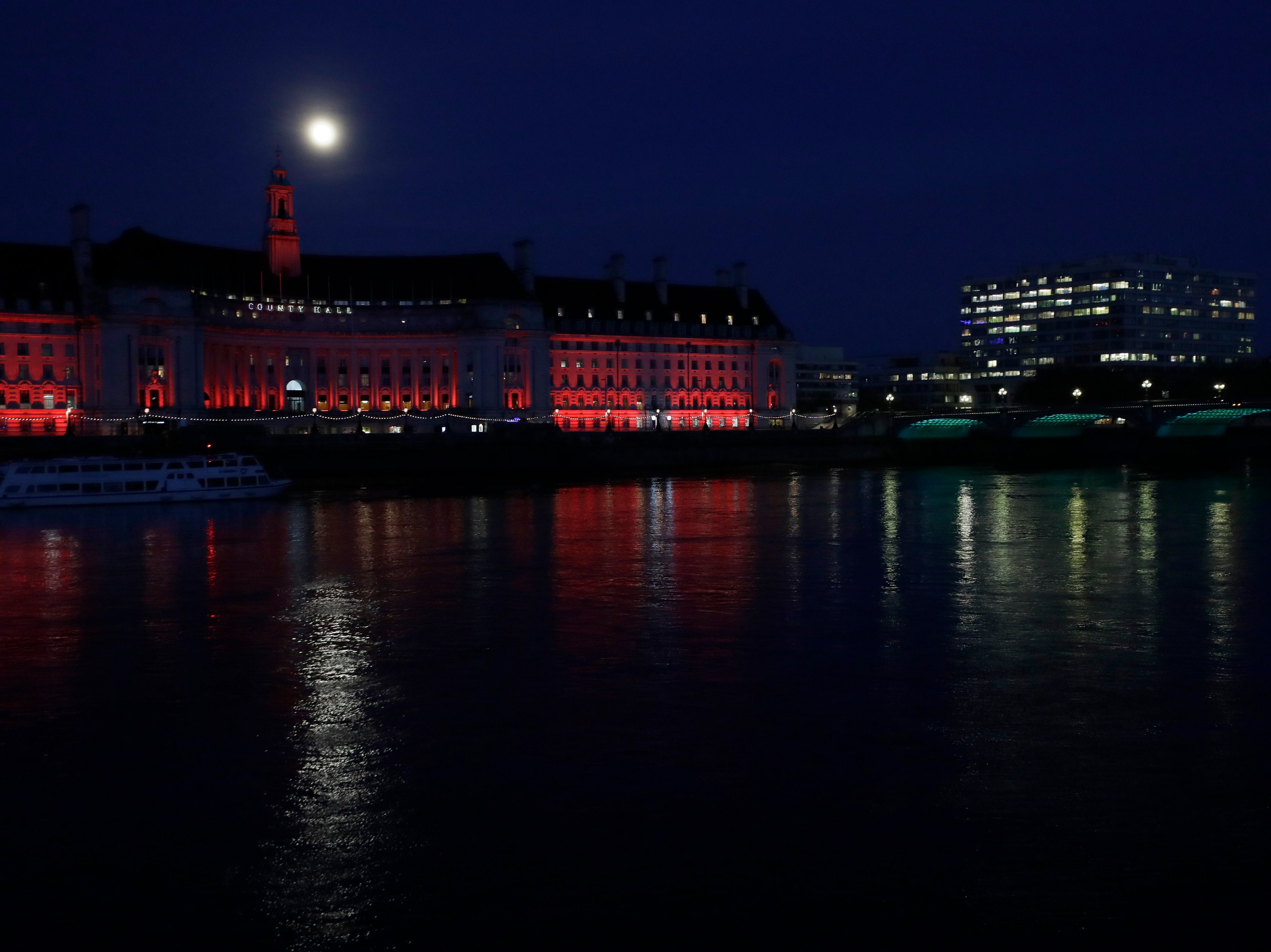 The moon rises through cloud over County Hall in London