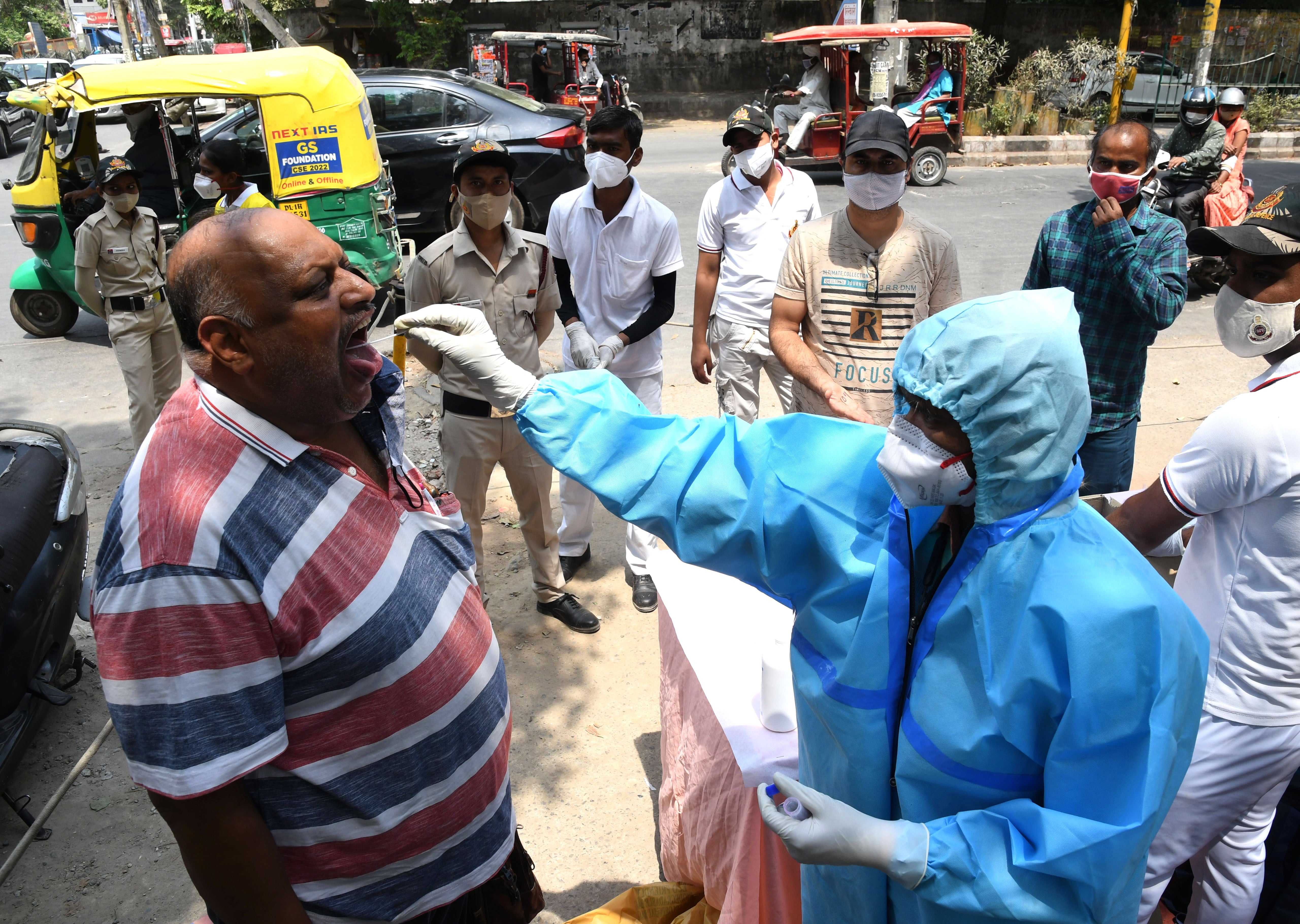 A health worker takes a swab sample to test for Covid-19 at a roadside testing centre in Delhi