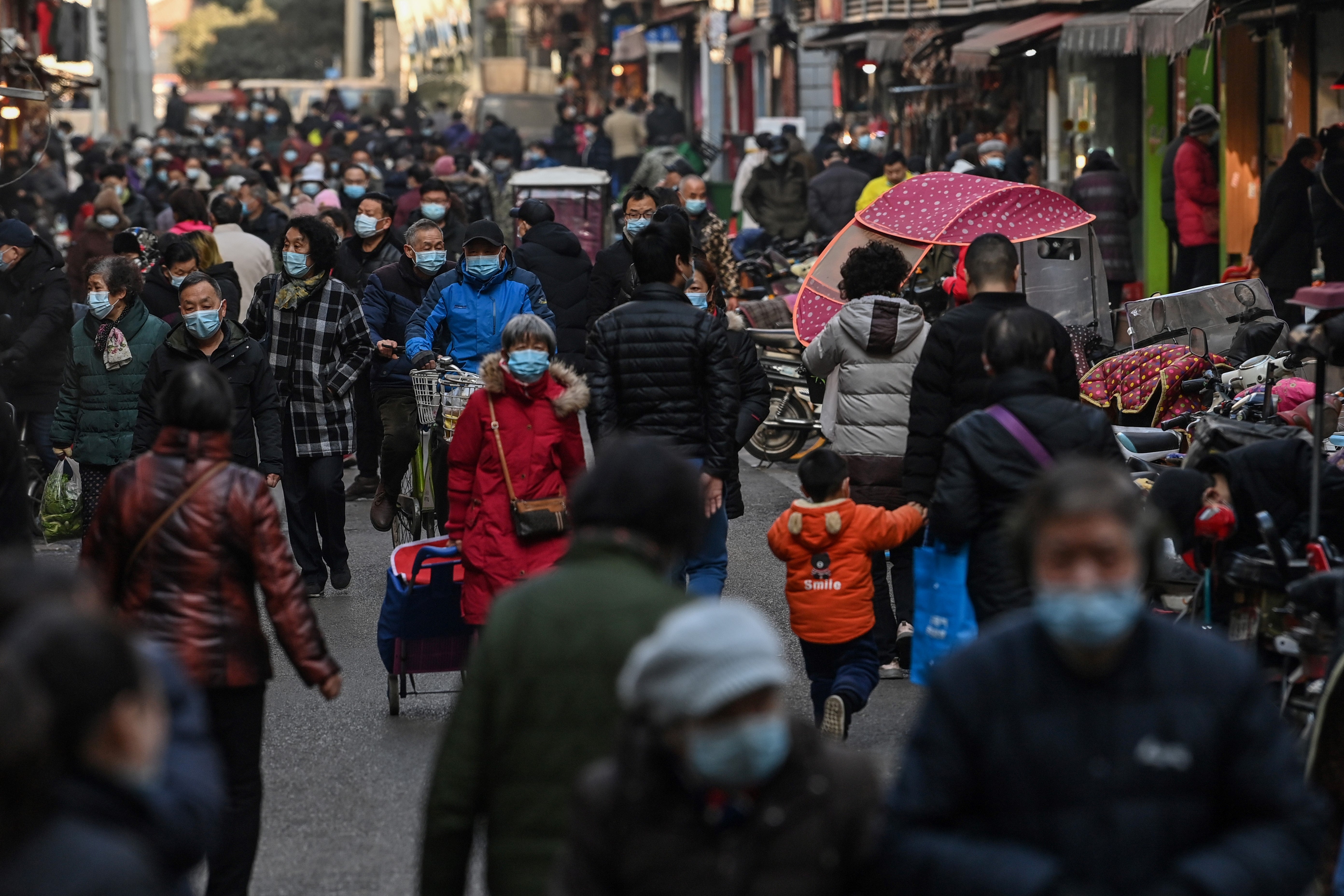 People walk along a street near a market in Wuhan, China's central Hubei province on 19 January, 2021.