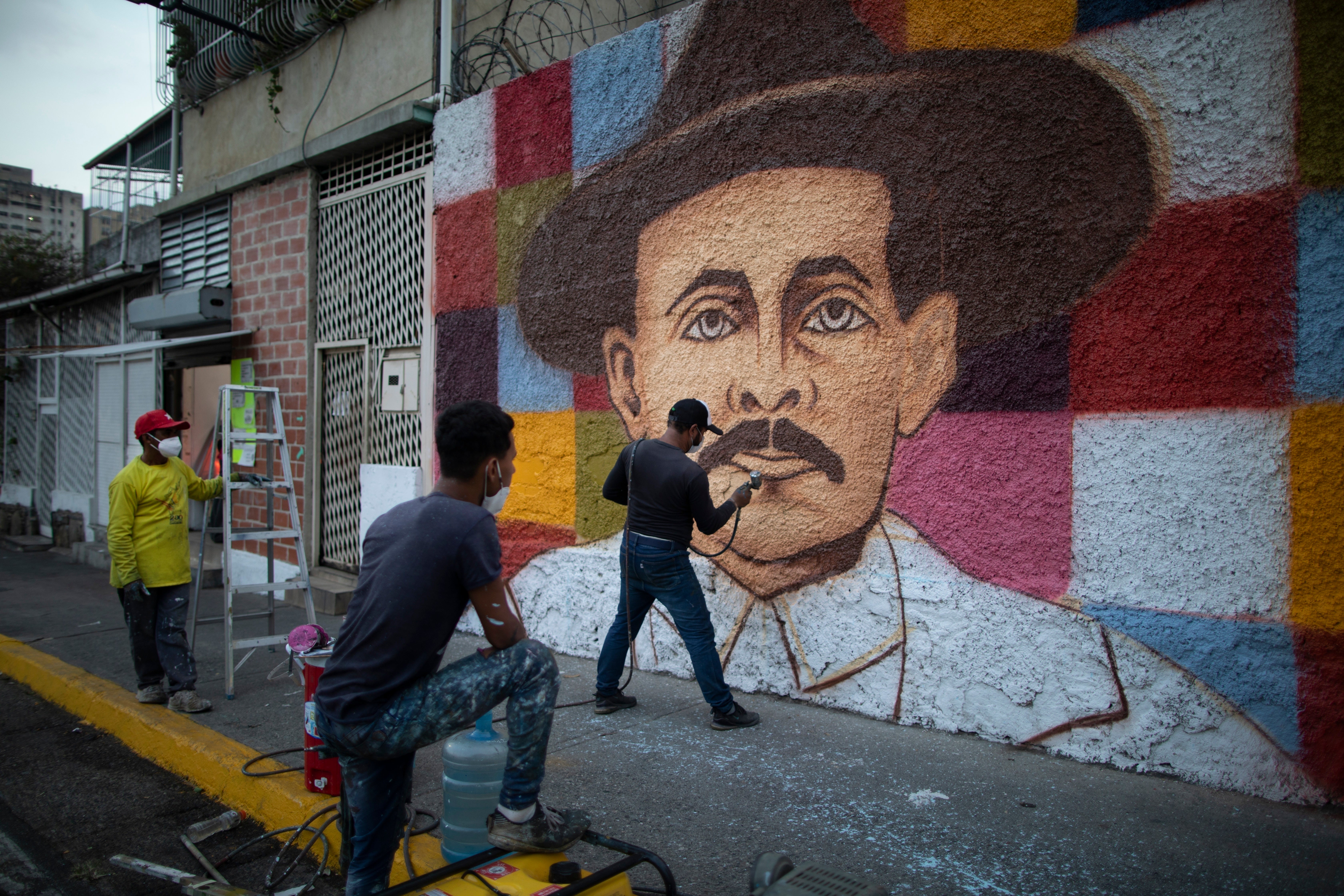 Venezuelan artist Miguel Garcia puts the finishing touches on his mural depicting José Gregorio Hernández