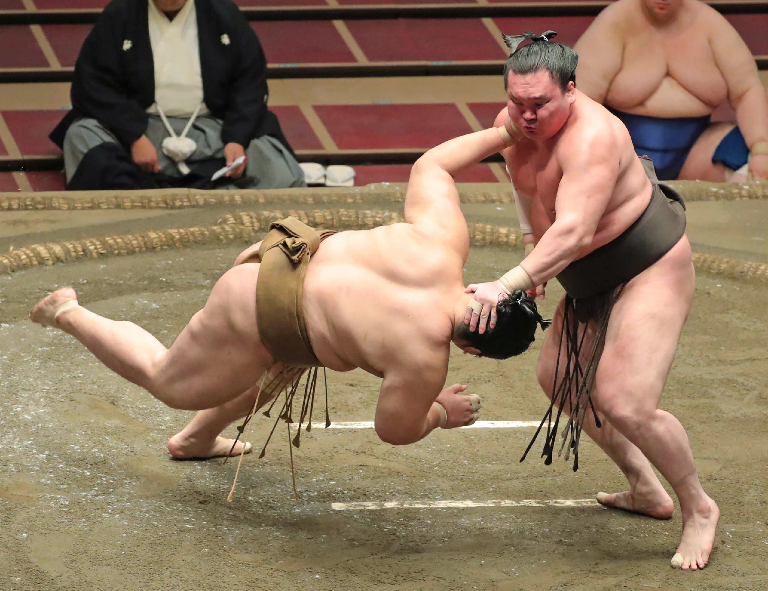 Yokozuna-ranked sumo wrestler Hakuho (R) pushes down opponent Kagayaki in the ring in 2020