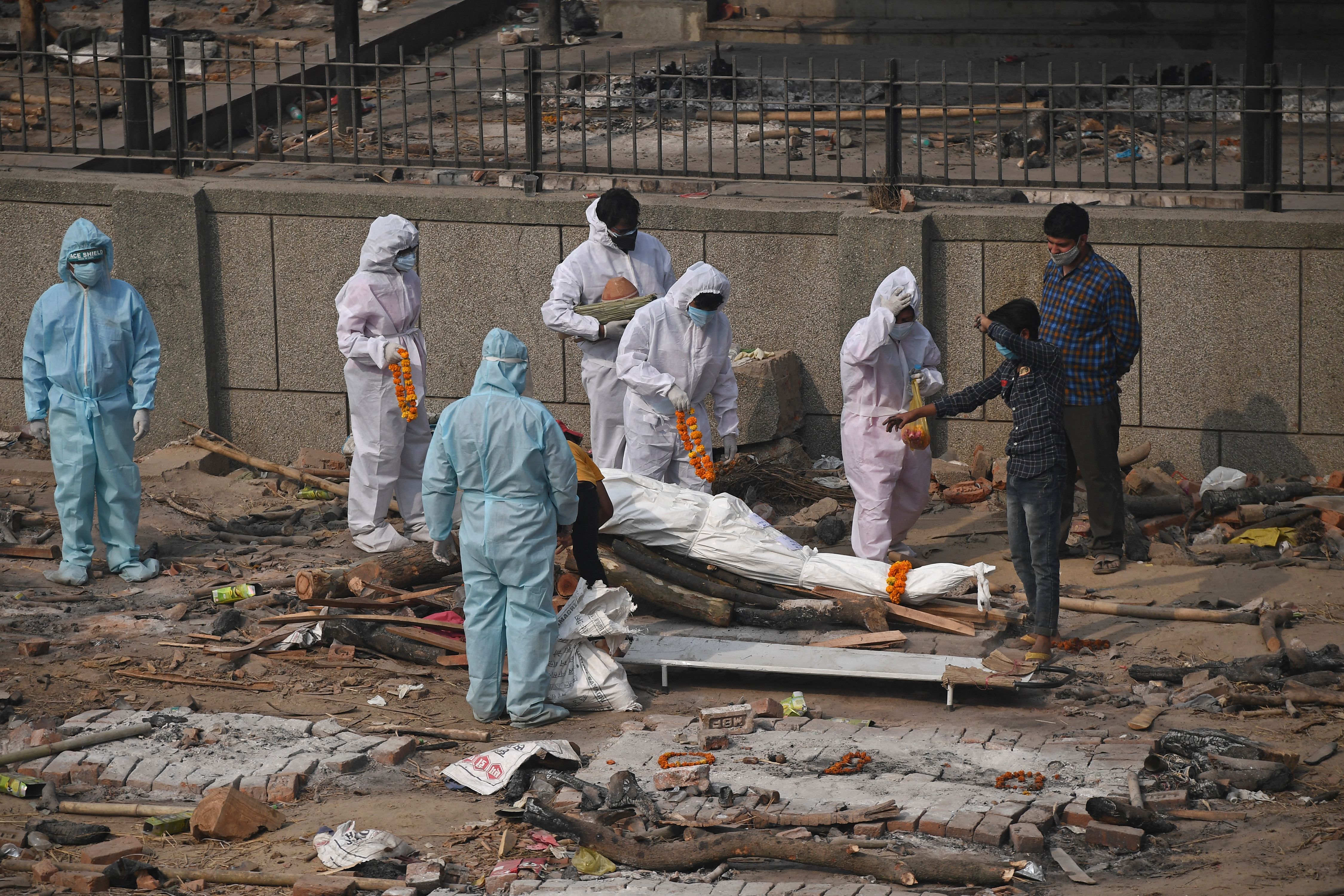 Relatives and friends wearing personal protective equipment (PPE) suits prepare the body of a victim who died due to the Covid-19