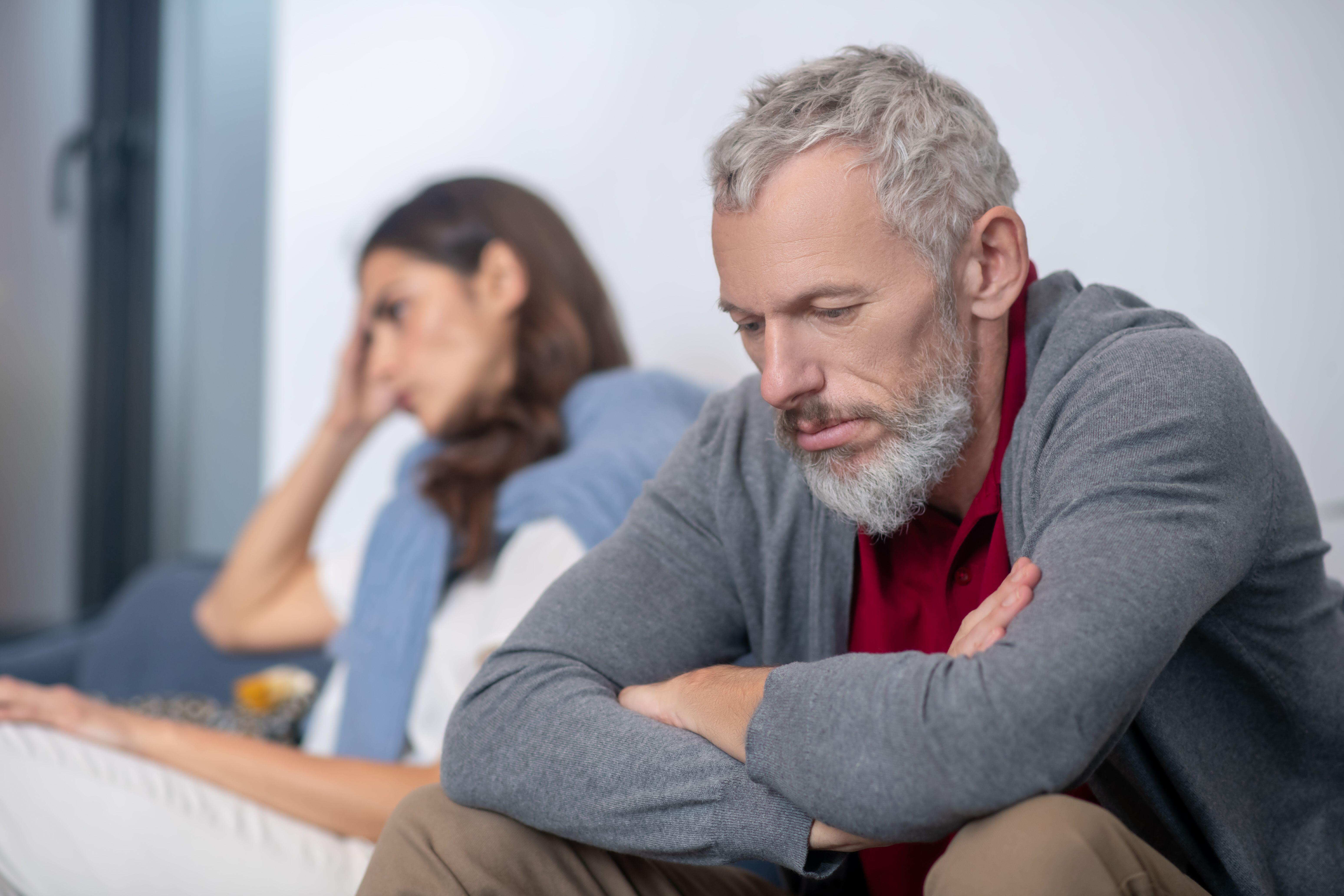 A man sits on a sofa, looking anxious