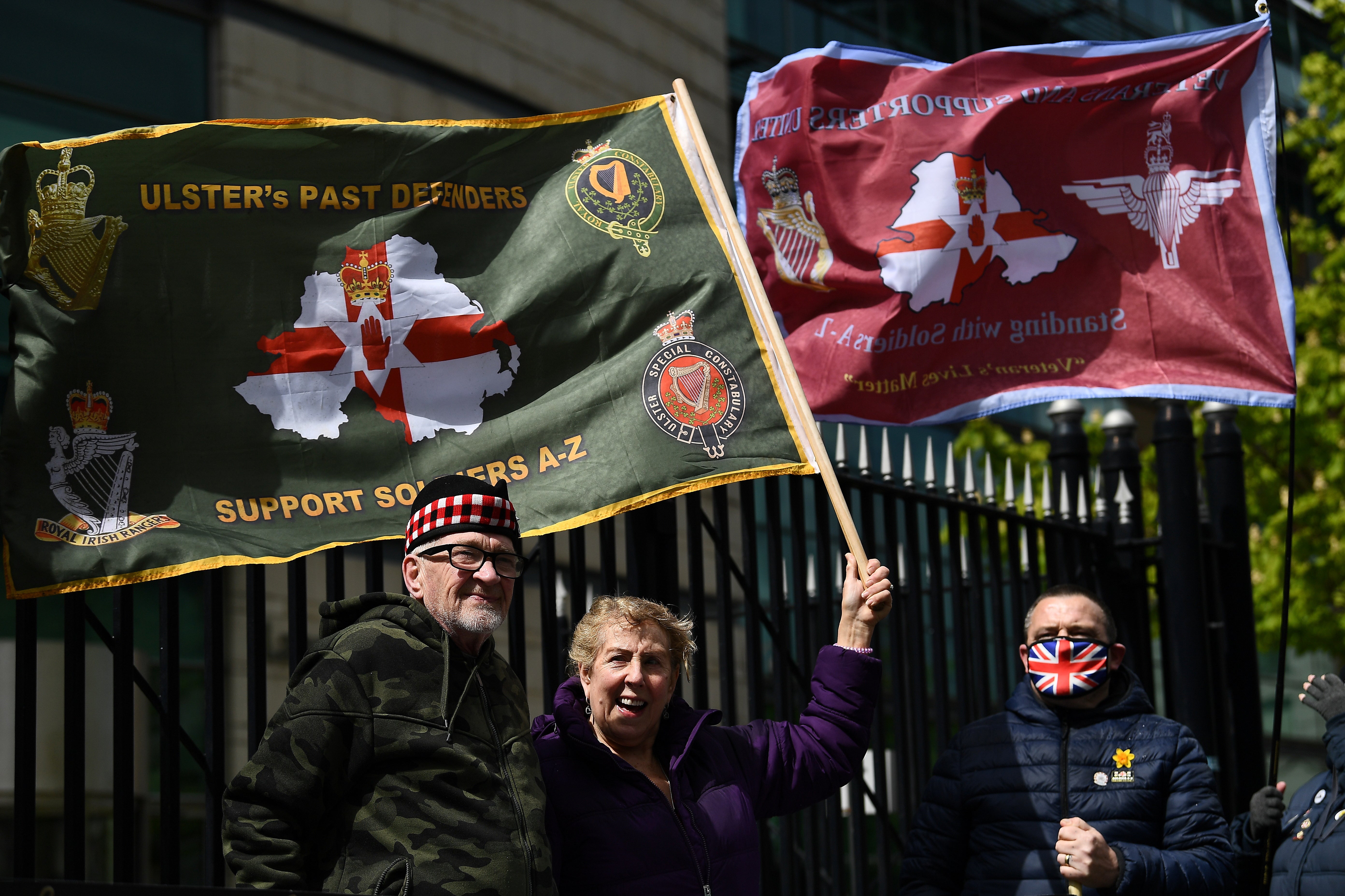 People hold flags outside Belfast’s Laganside Courts during the trial into the 1972 killing of official IRA member Joe McCann, on Tuesday (4 May)