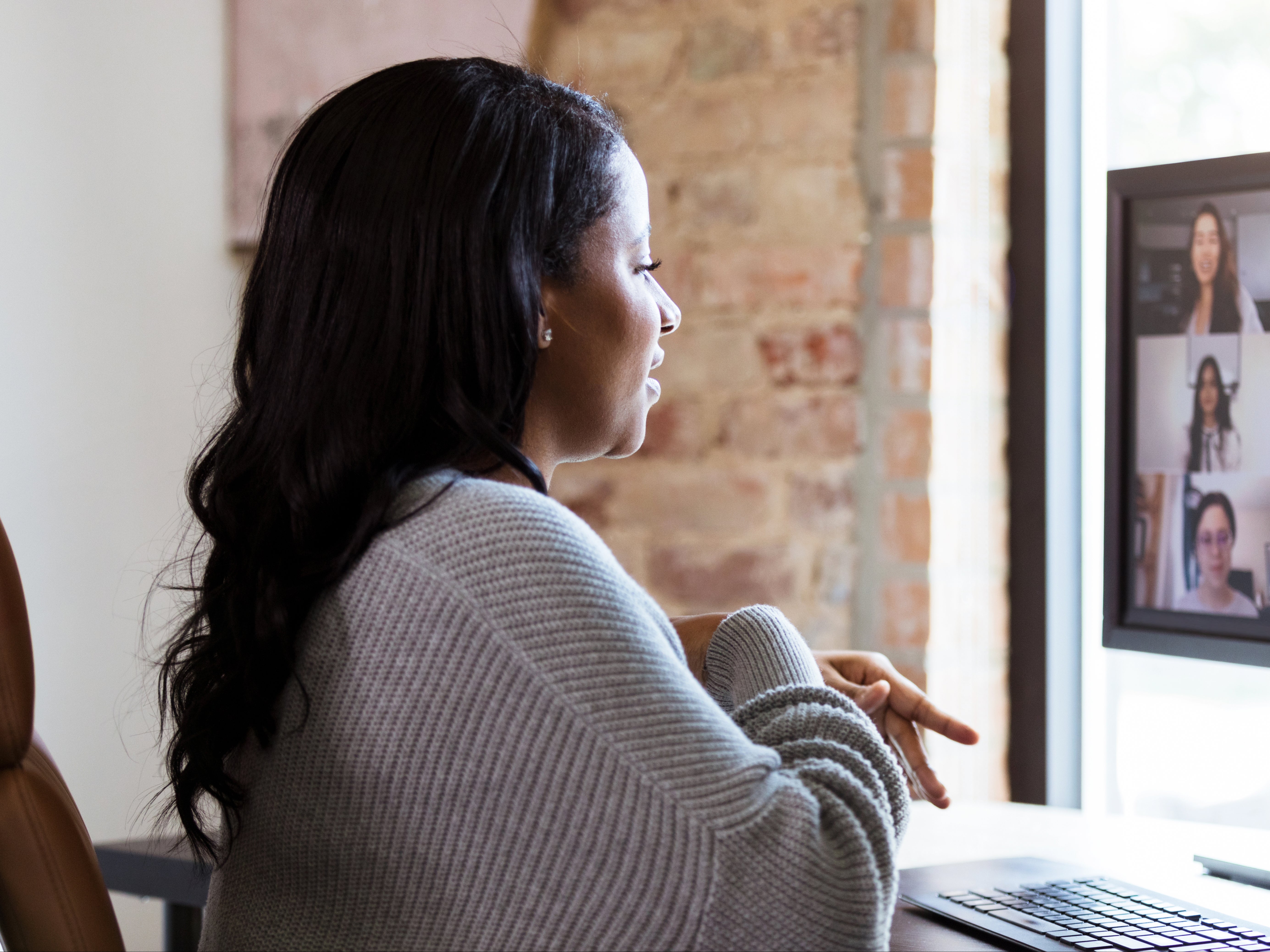 A woman uses video conferencing to chat with colleagues