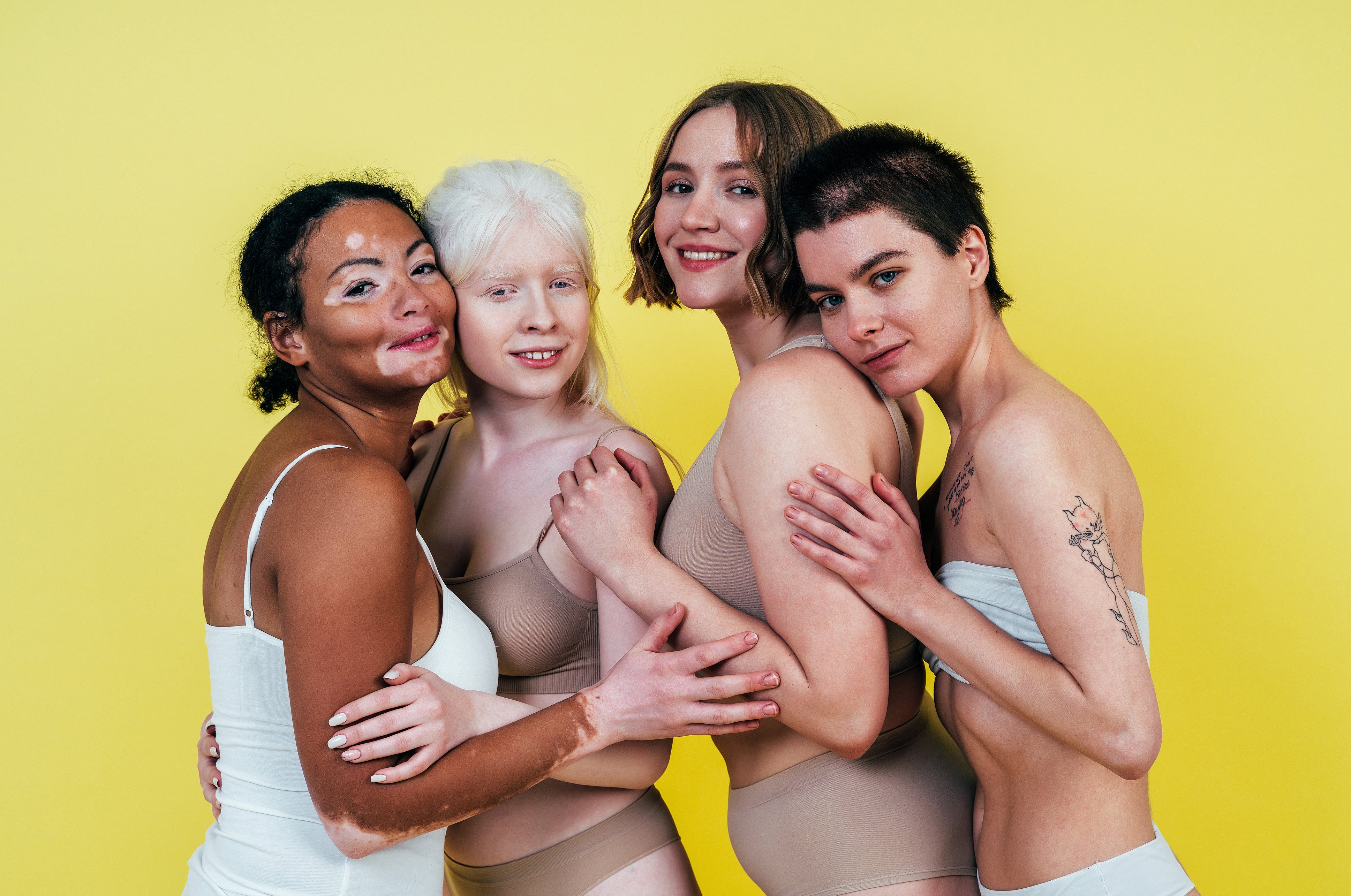 A group of multi-ethnic women with varying skin tones pose together to promote body positivity and self-acceptance