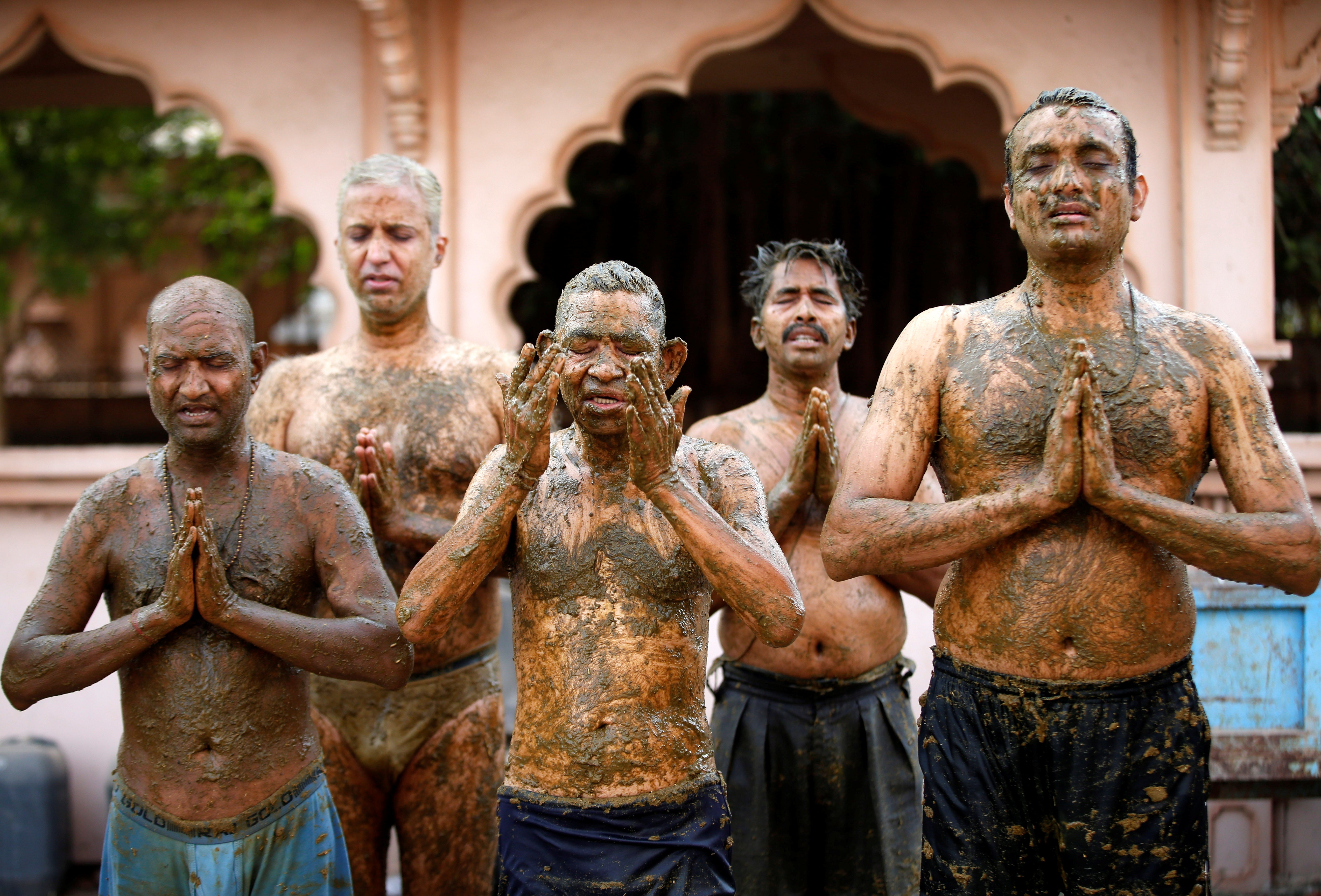 Worshippers pray after applying cow dung to their bodies on the outskirts of Ahmedabad