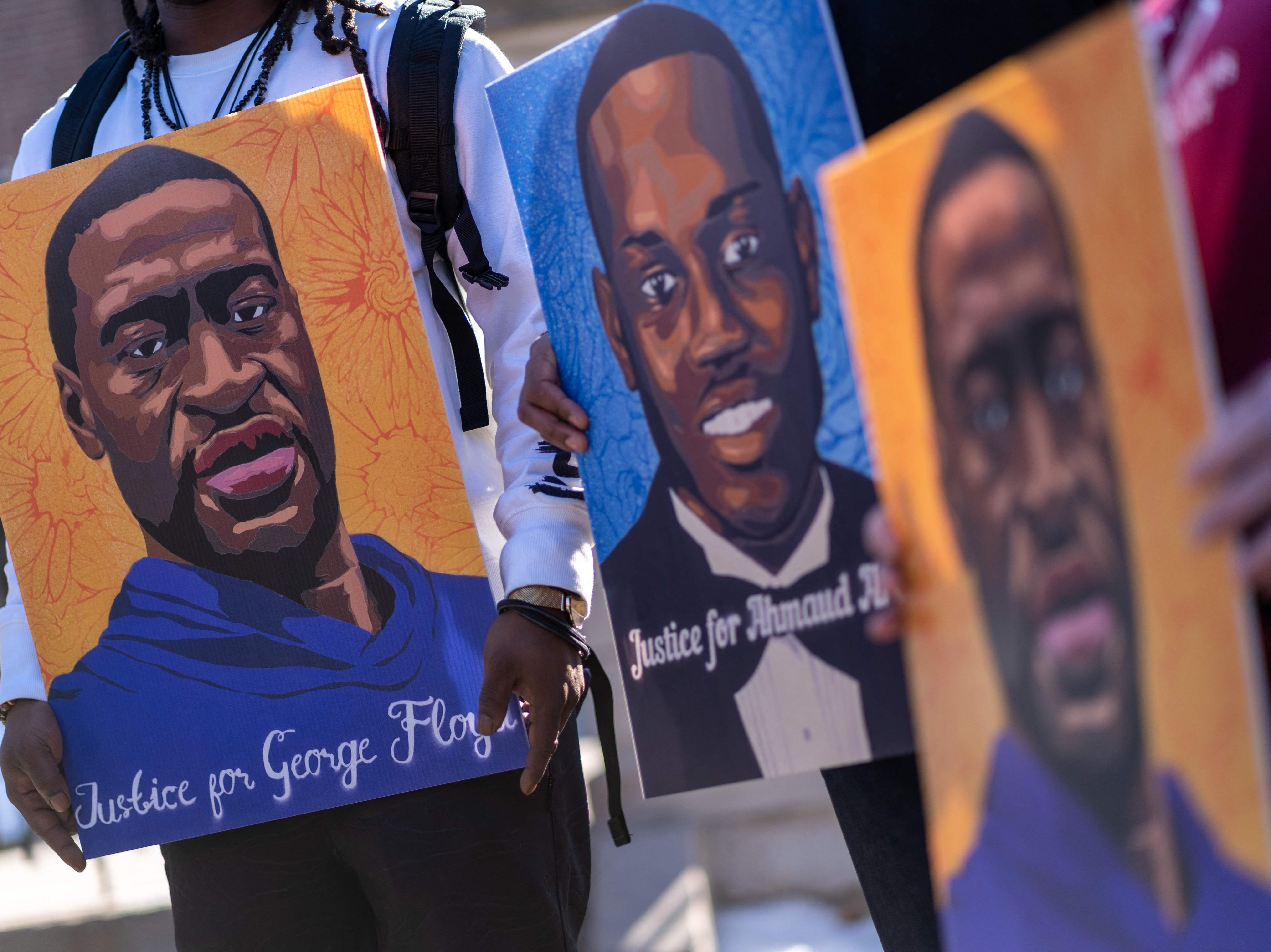 Community activists hold pictures of George Floyd and Ahmaud Arbery outside outside Minnesota Governor's residence