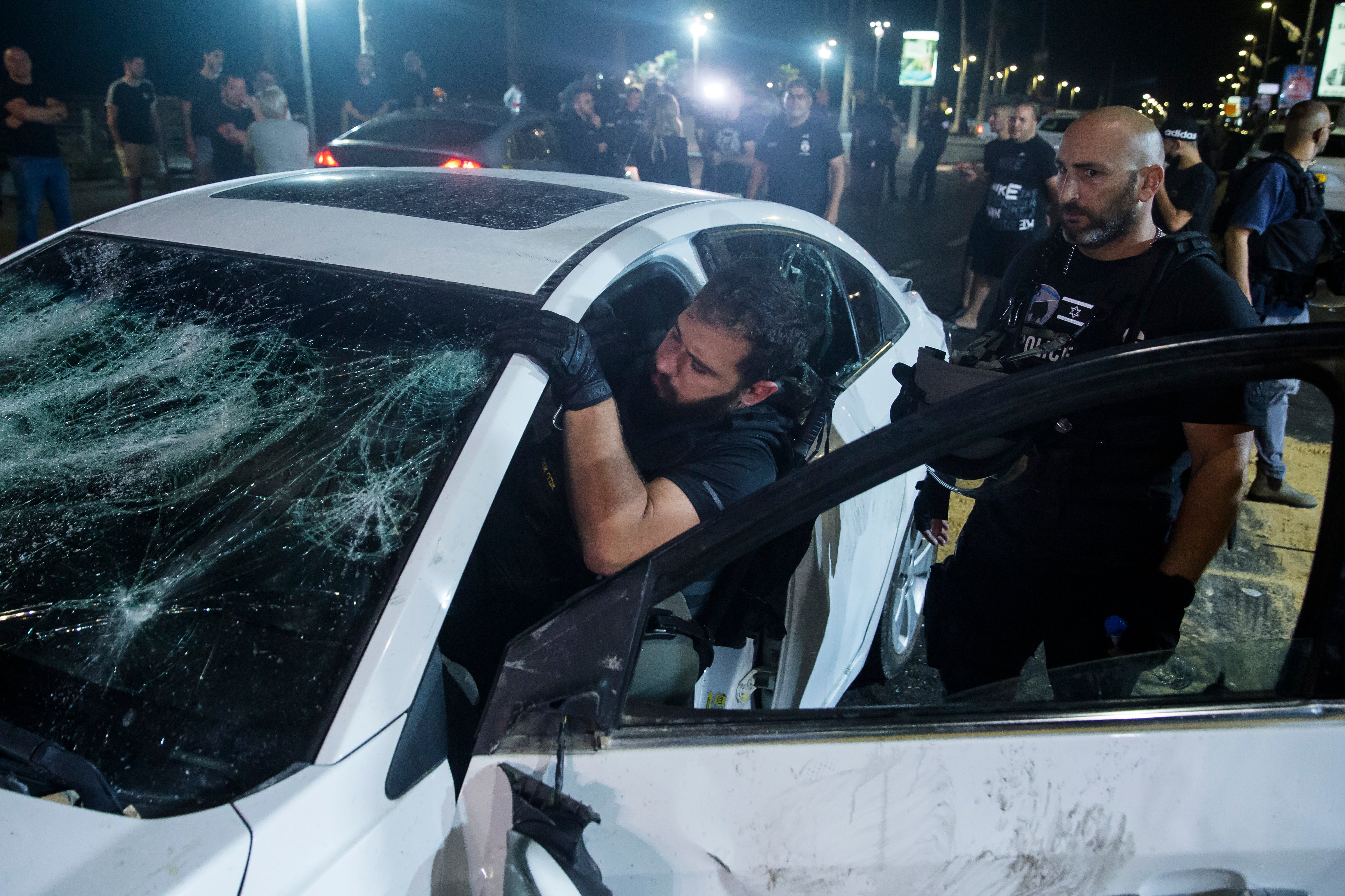 An Israeli police officer inspects the car of an Israeli Arab man who was attacked and injured by a mob