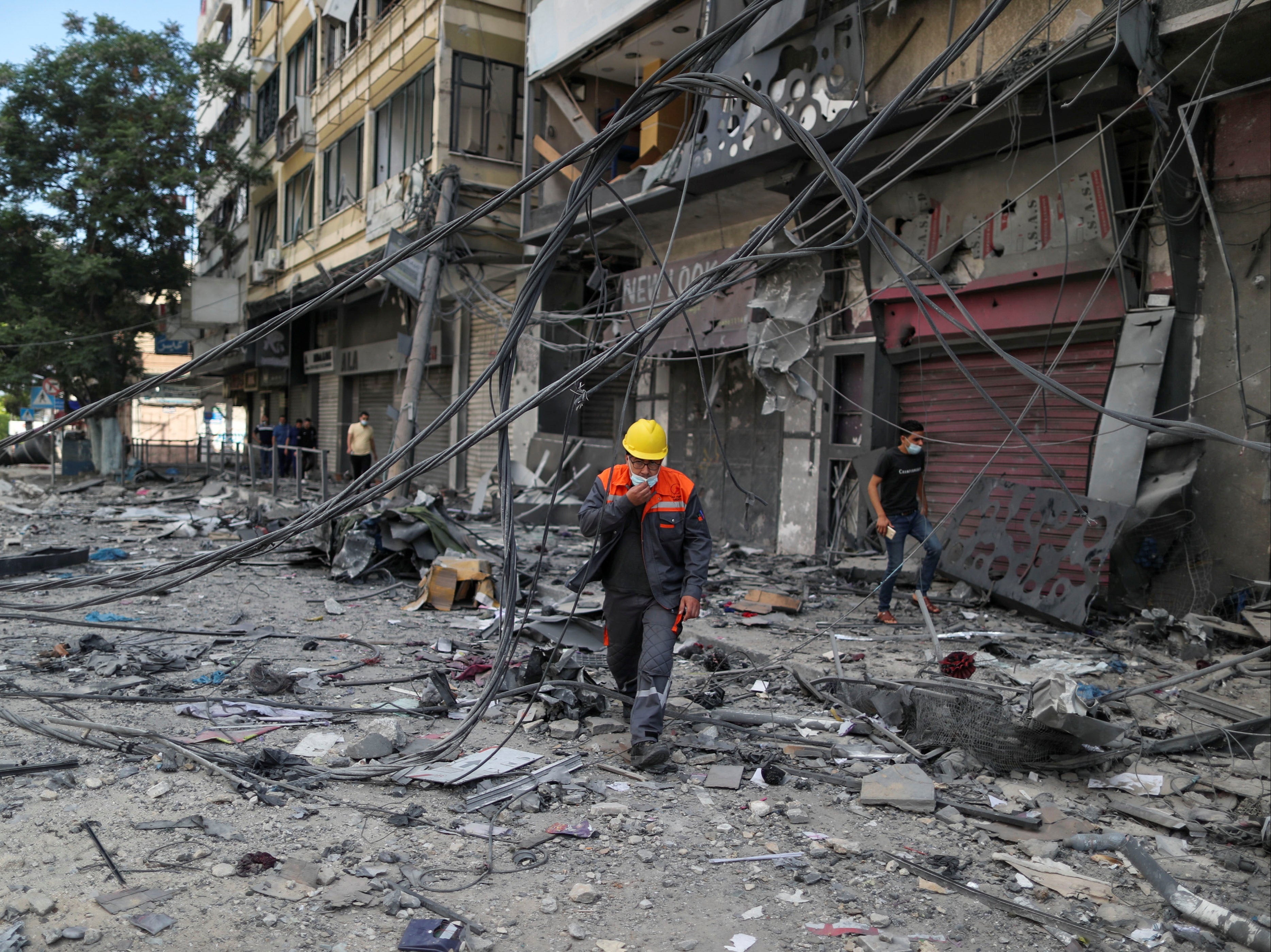 A Palestinian electricity worker walks at the site where a tower building was destroyed by Israeli air strikes, amid a flare-up of Israeli-Palestinian violence, in Gaza City