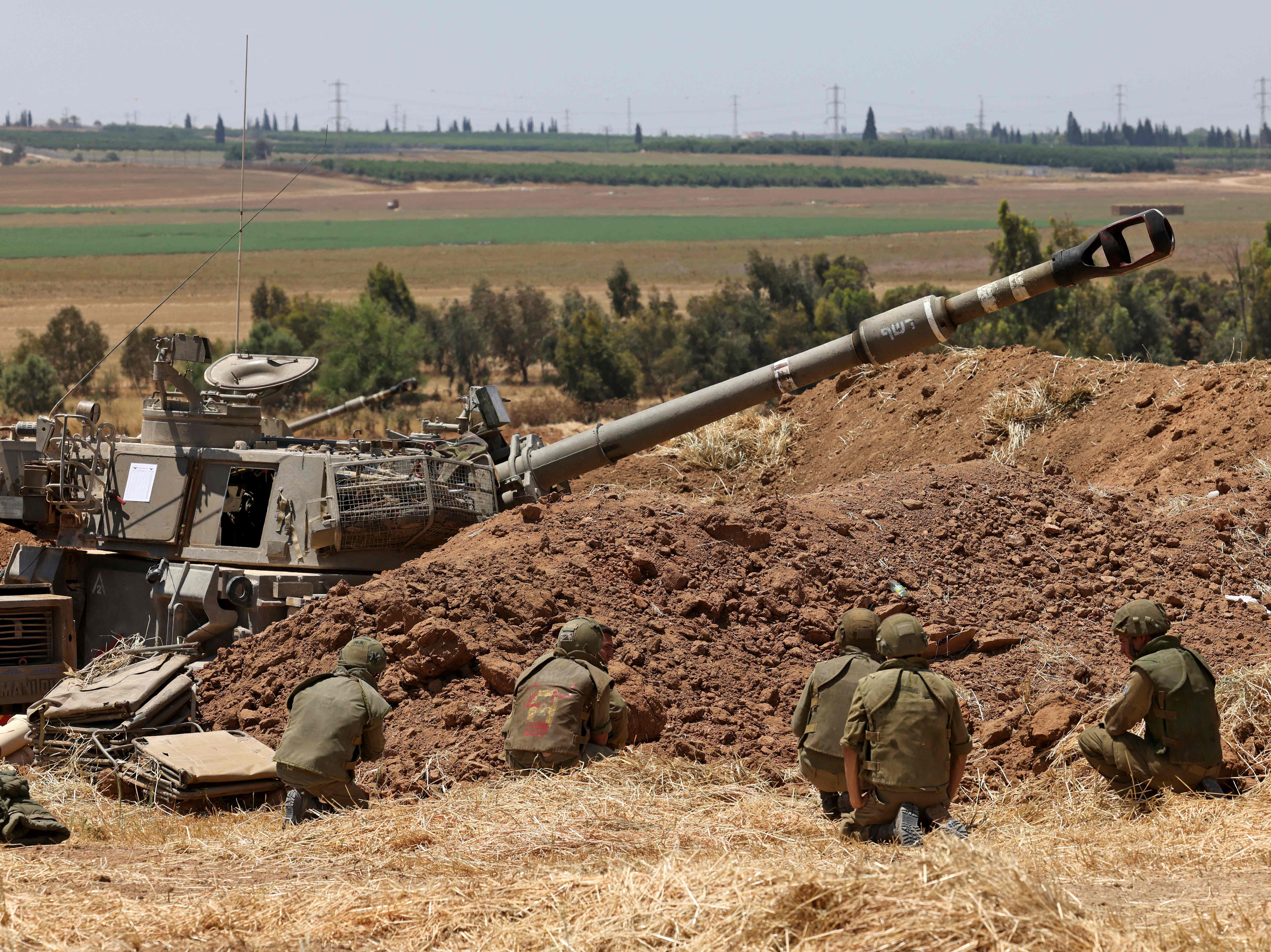 Israeli soldiers take cover at their position near Sderot in southern Israel on the border with the Hamas-controlled Gaza Strip during shelling