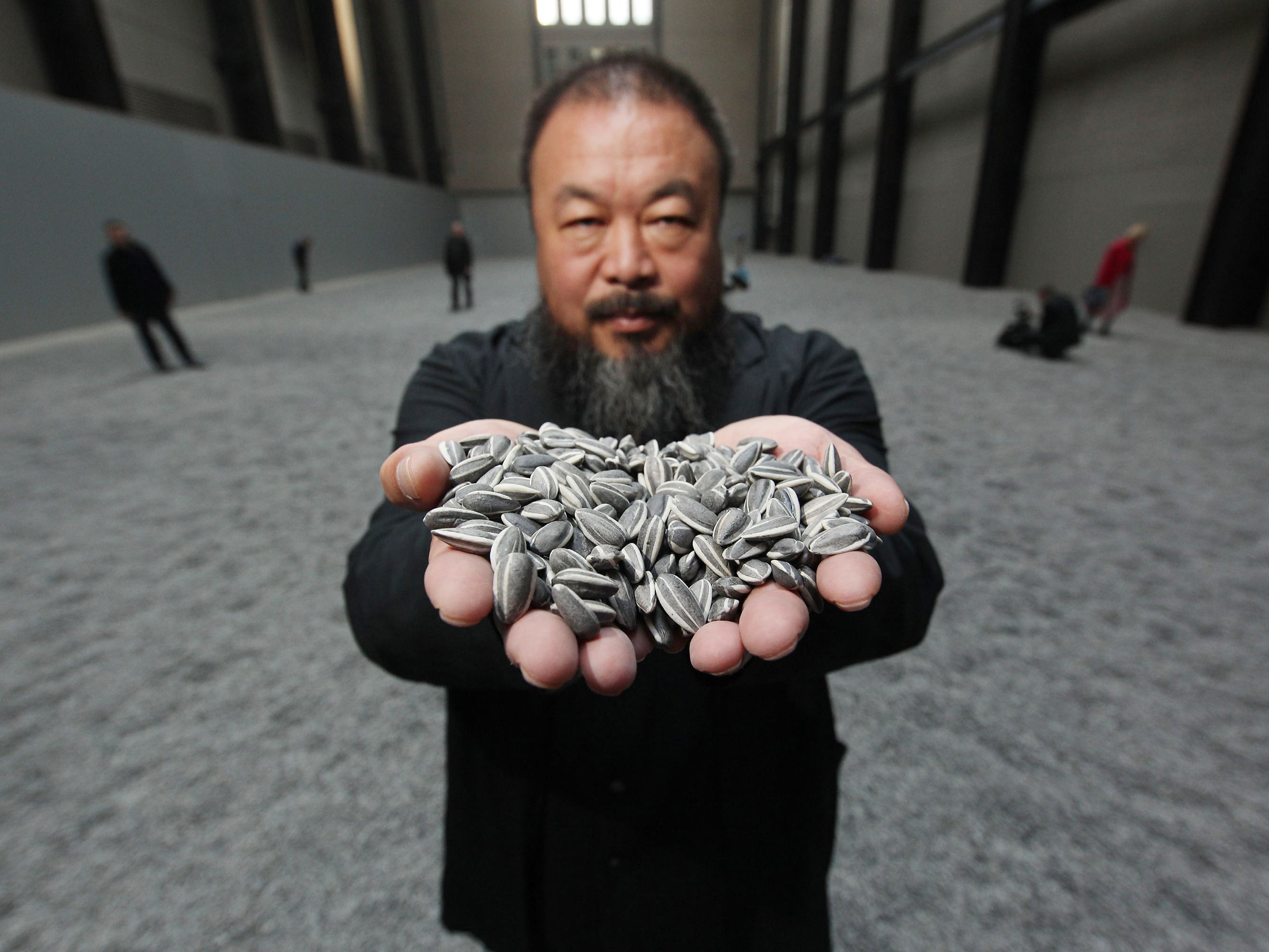 Ai Weiwei holds some seeds from his Unilever installation Sunflower Seeds at Tate Modern, October 2010